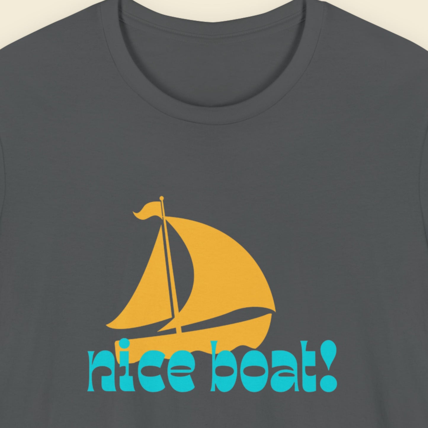 Gray t-shirt with a yellow sailboat graphic and 'nice boat!' text on a beige background.