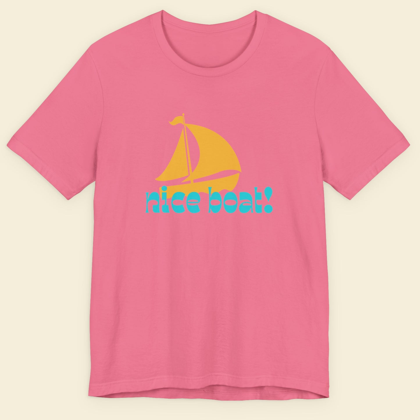 Pink t-shirt with a yellow sailboat and blue text on a beige background.
