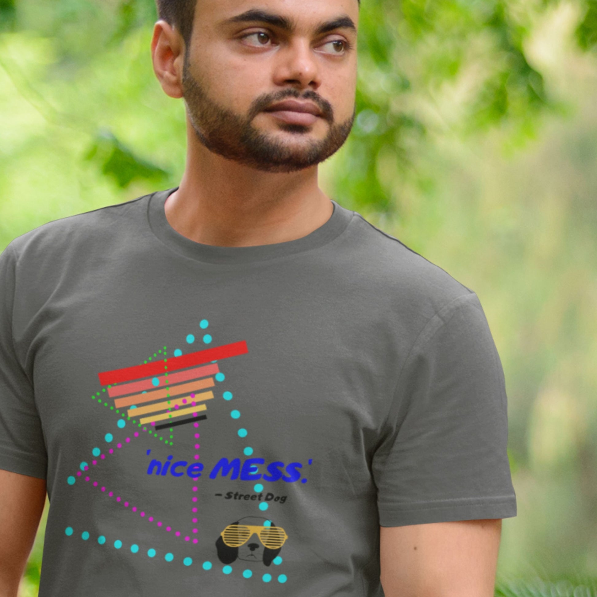 Man wearing a dark gray t-shirt with colorful design and text outdoors.