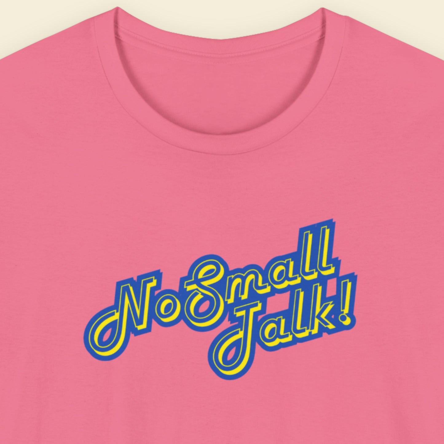 Pink t-shirt with yellow and blue 'No Small Talk!' text on a beige background.