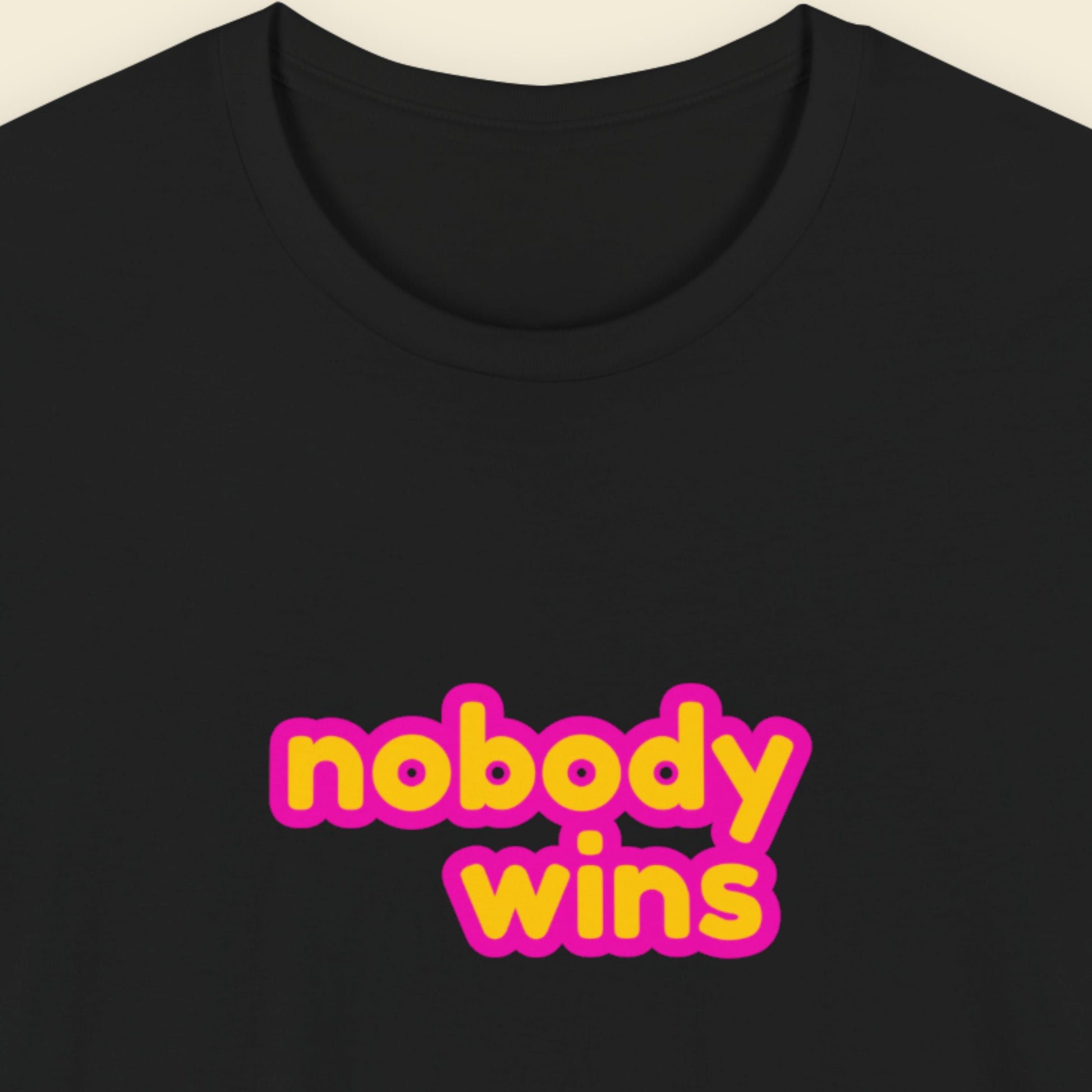 Black tee with multicolored 'nobody wins' text on a beige background.