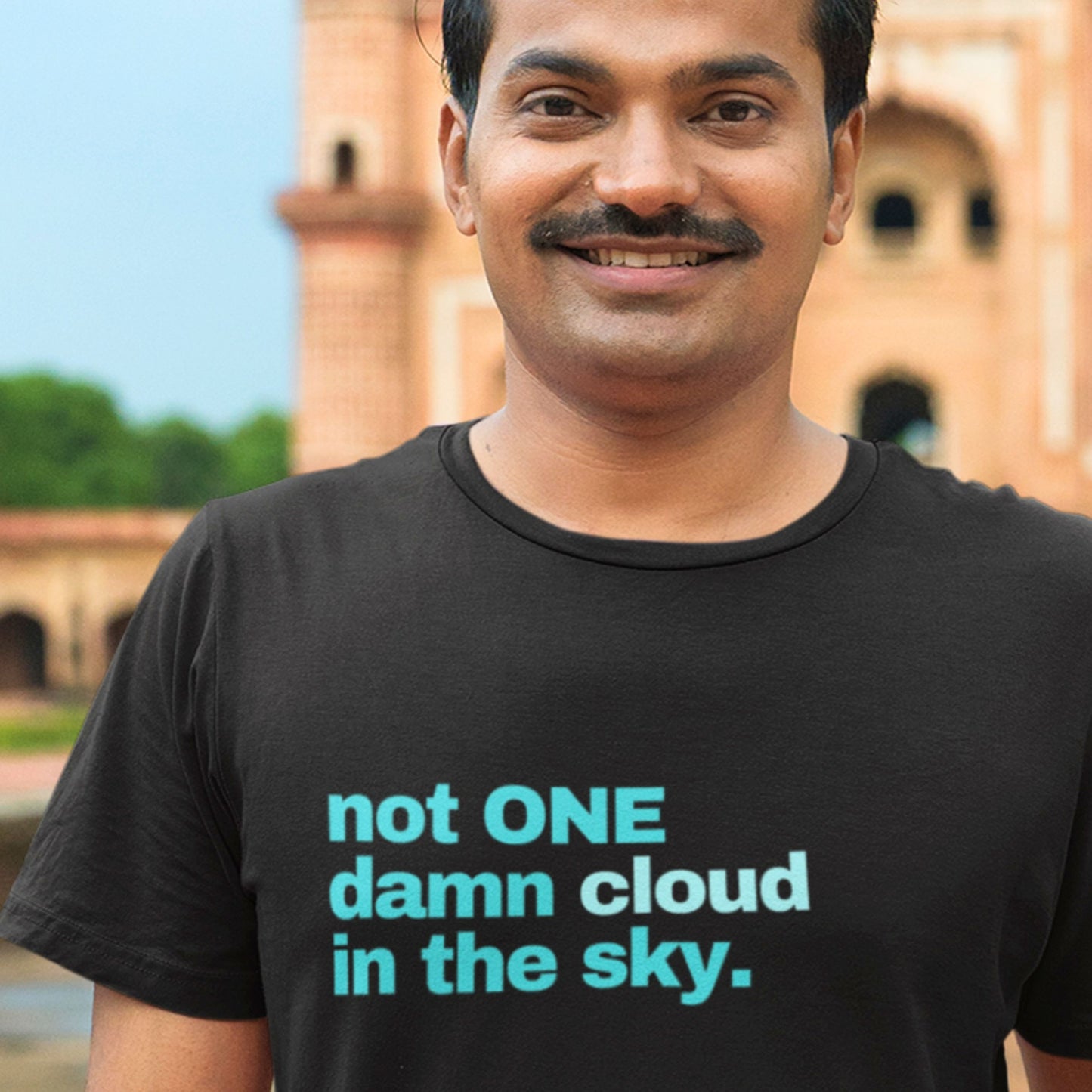 Man wearing a black t-shirt with blue text standing in front of a building.