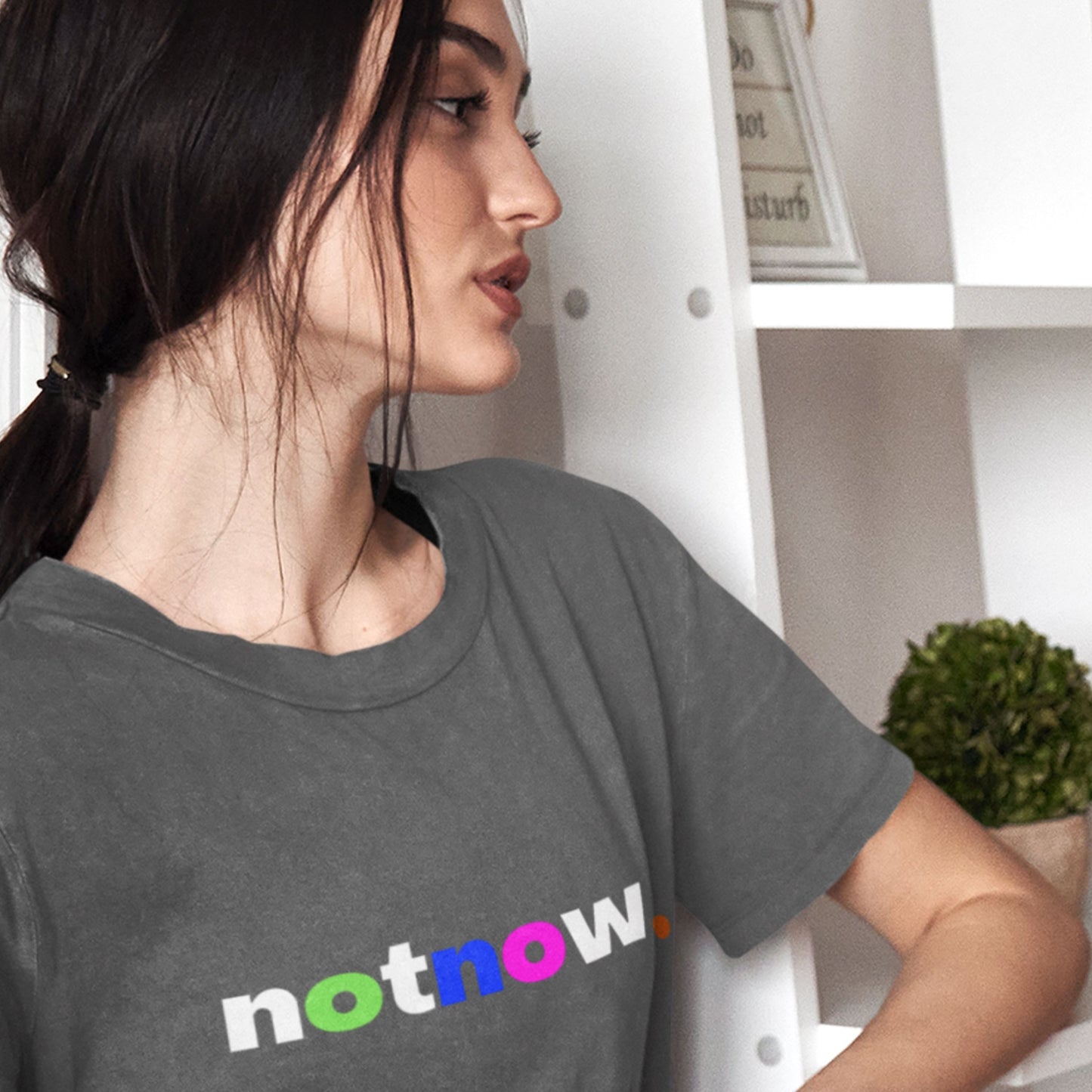 Woman wearing a gray t-shirt with 'not now' text.