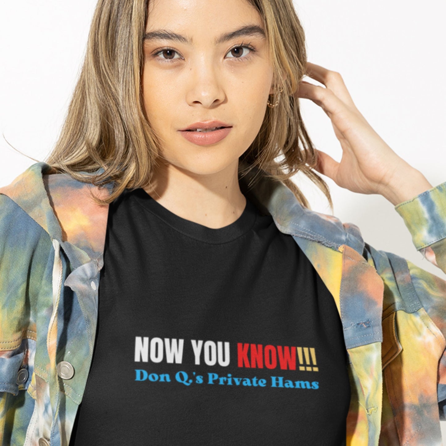 Woman wearing a black t-shirt with multicolored 'now you know!!!' text on a grey background.