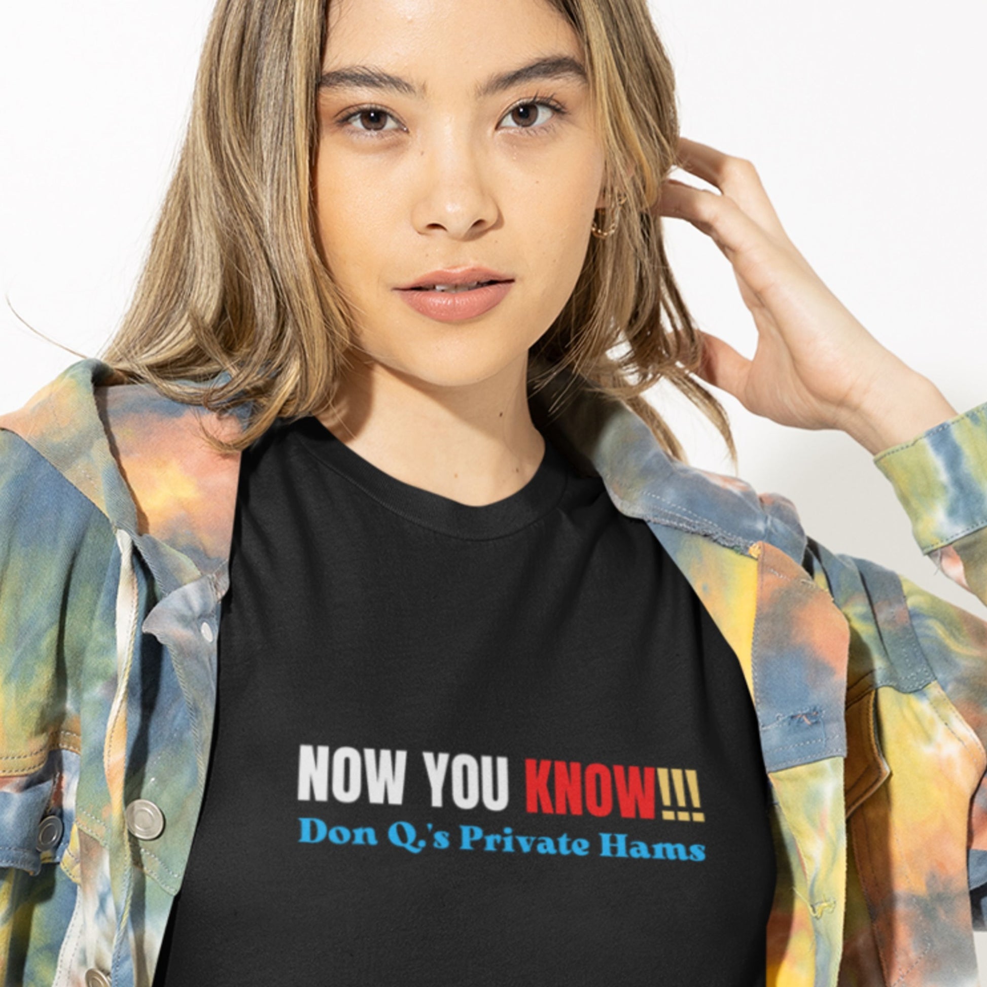 Woman wearing a black t-shirt with multicolored 'now you know!!!' text on a grey background.