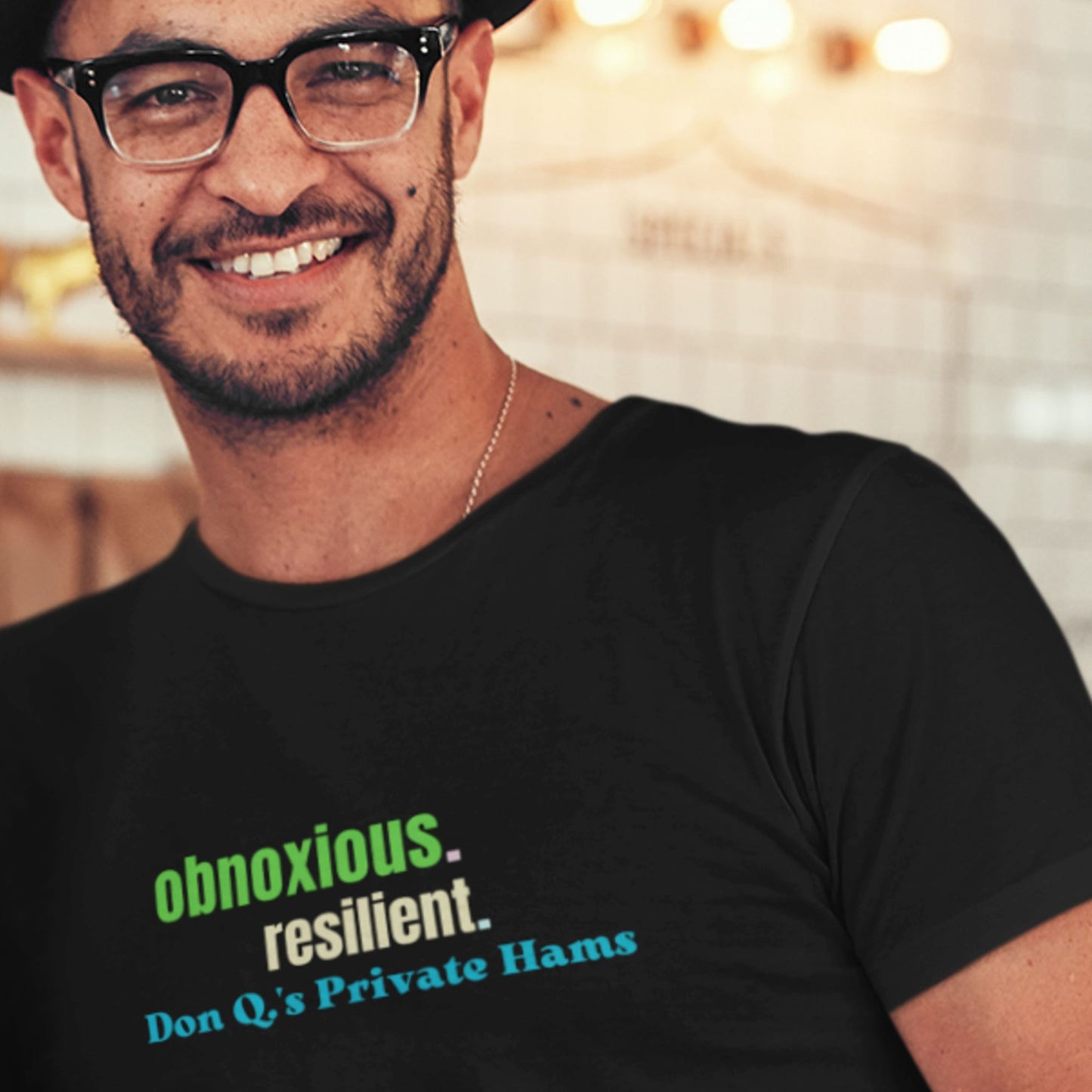 Man wearing a black t-shirt with text, smiling in front of a blurred background.