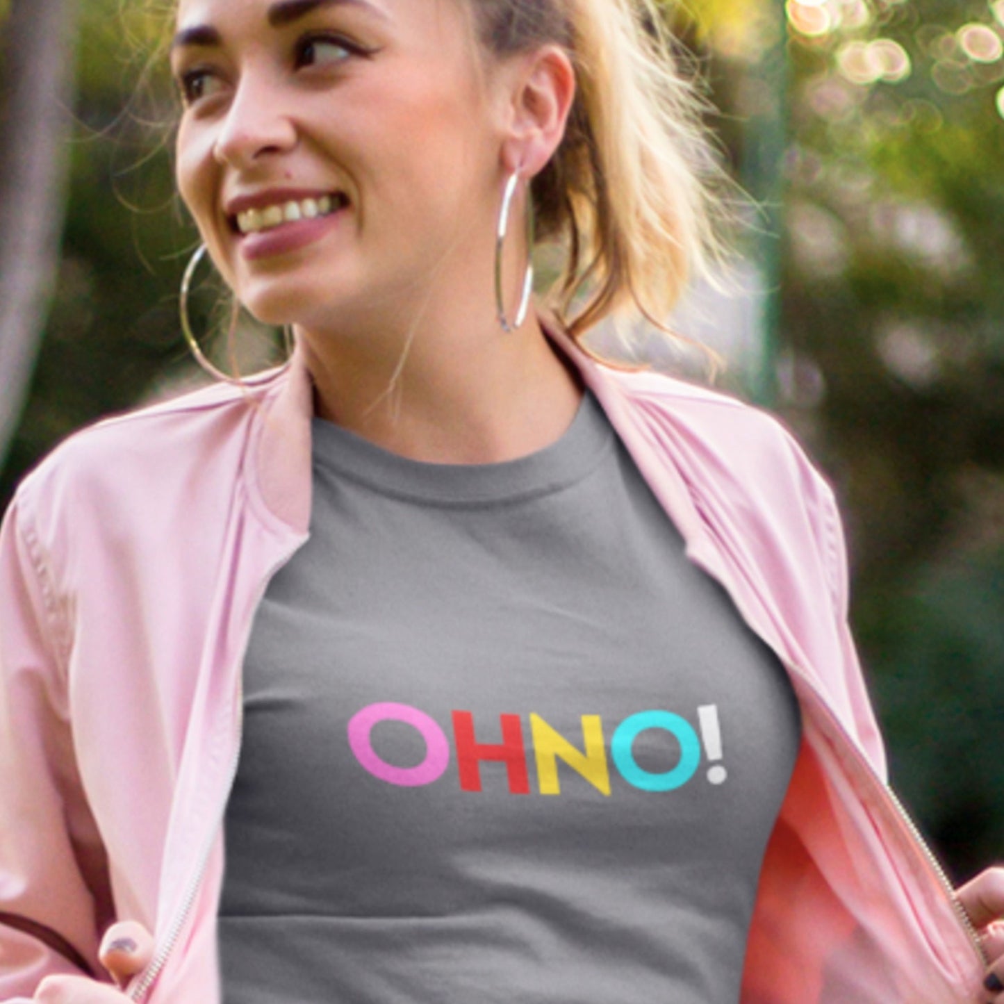 Woman wearing a gray t-shirt with 'OHNO!' in colorful letters, outdoors.