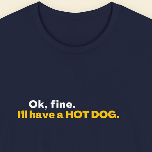 Navy blue t-shirt with text 'Ok, fine. I'll have a HOT DOG.' in white and yellow on a beige background.