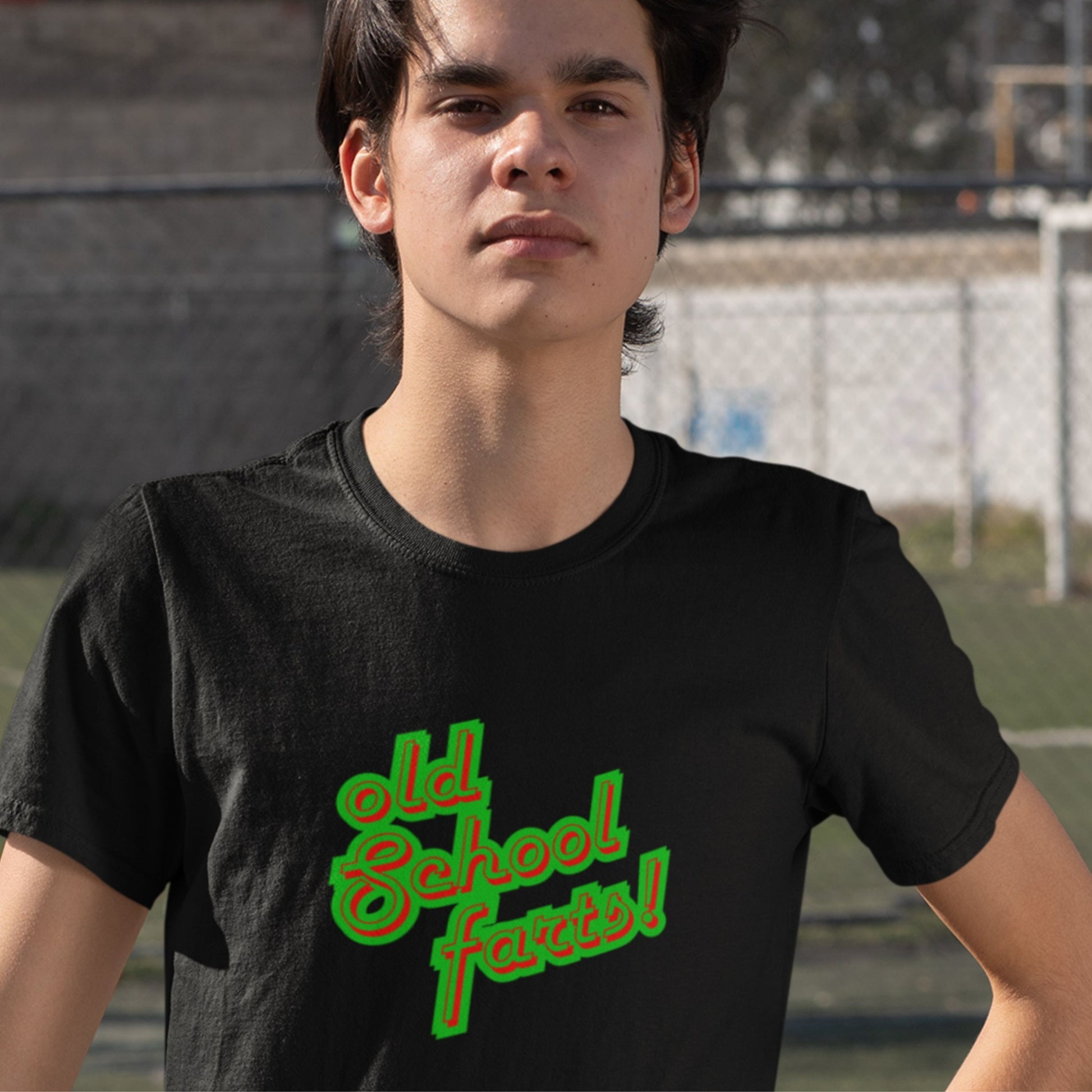 Man wearing a black t-shirt with humorous colorful text outdoors.
