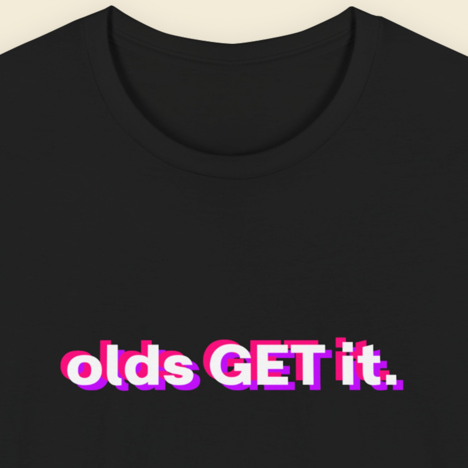 Black t-shirt with colorful text 'olds GET it.' on a beige background.