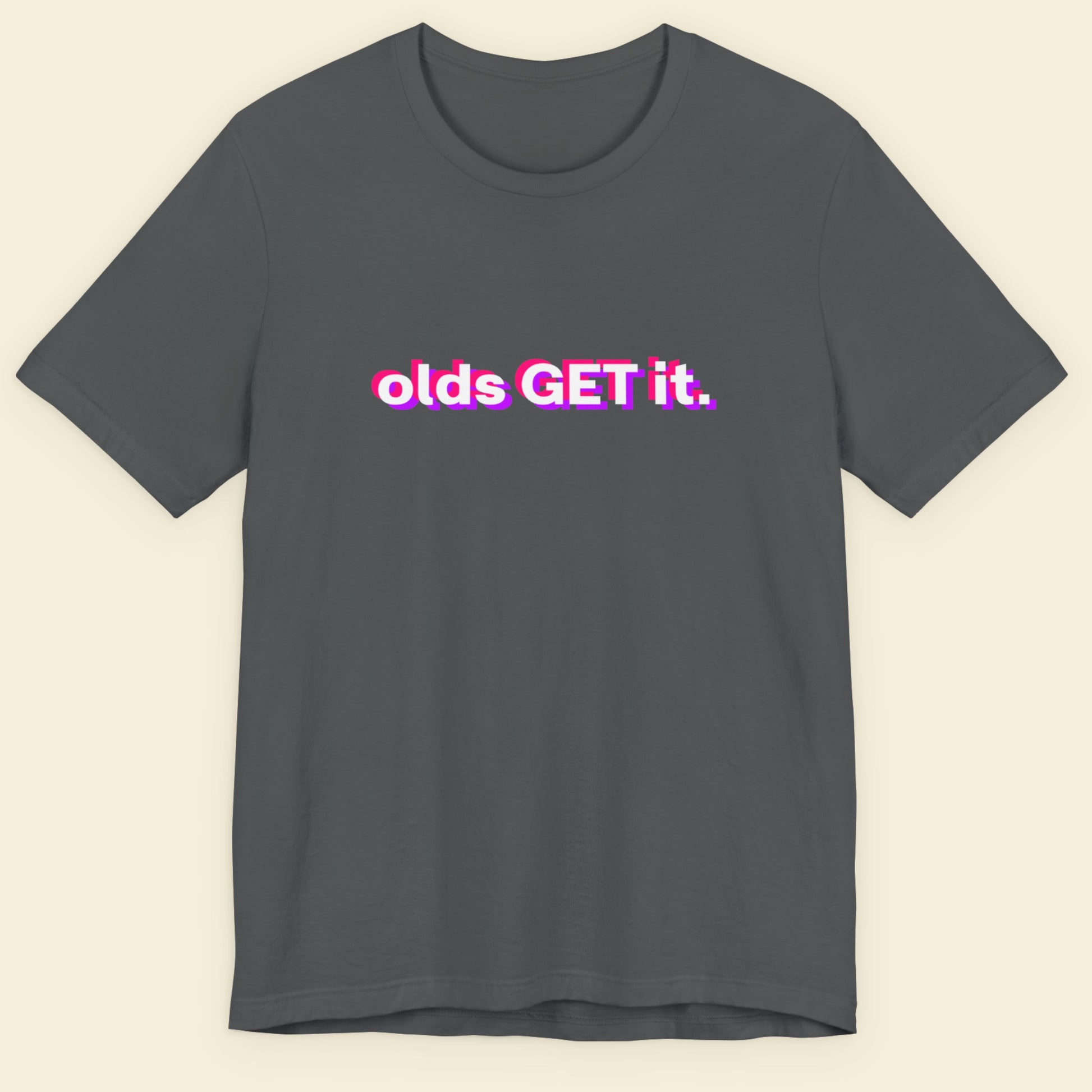 Gray t-shirt with 'olds GET it.' text in pink and white on a beige background.