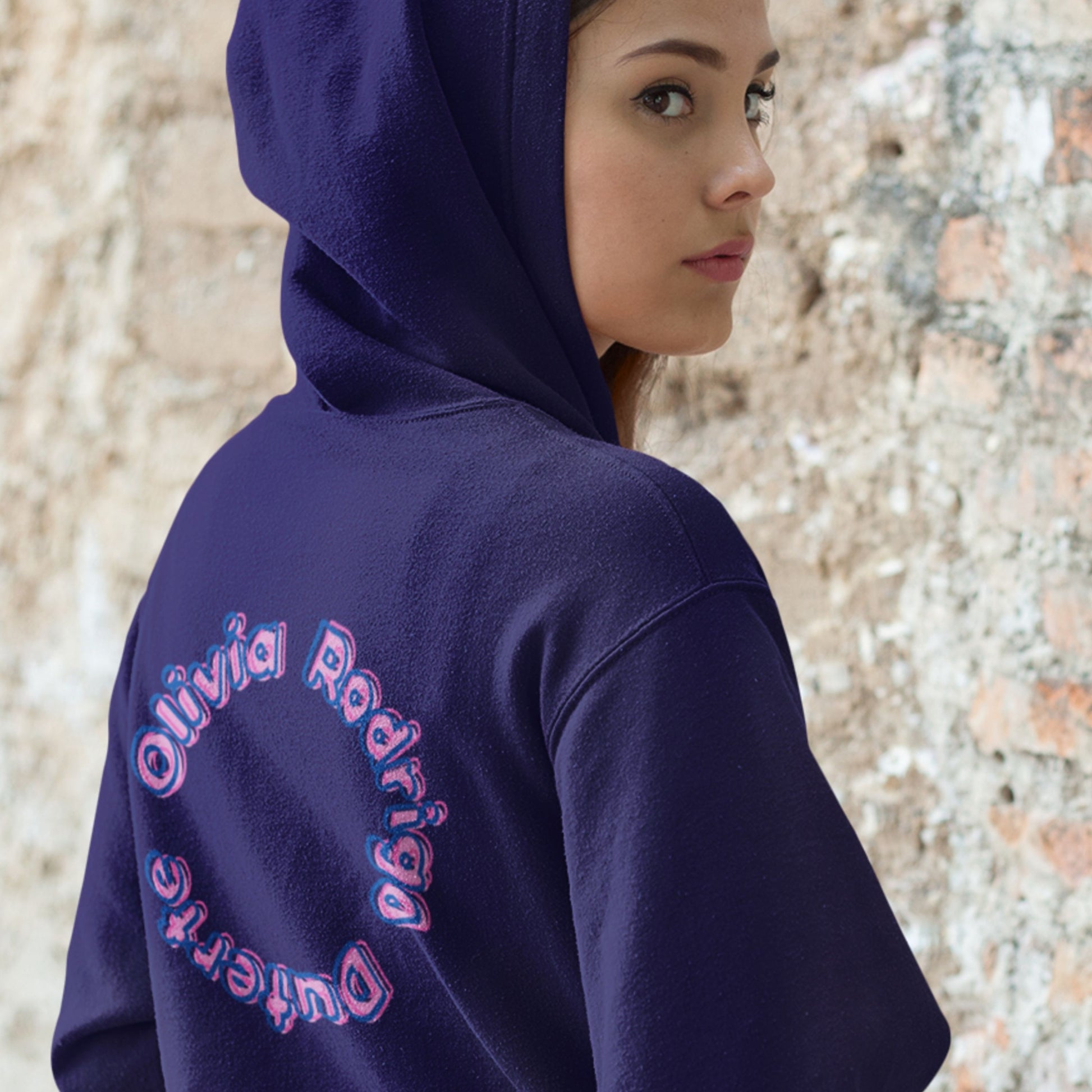Person wearing a navy hoodie with 'Olivia Rodrigo Duterte' text on the back, standing against a textured wall.
