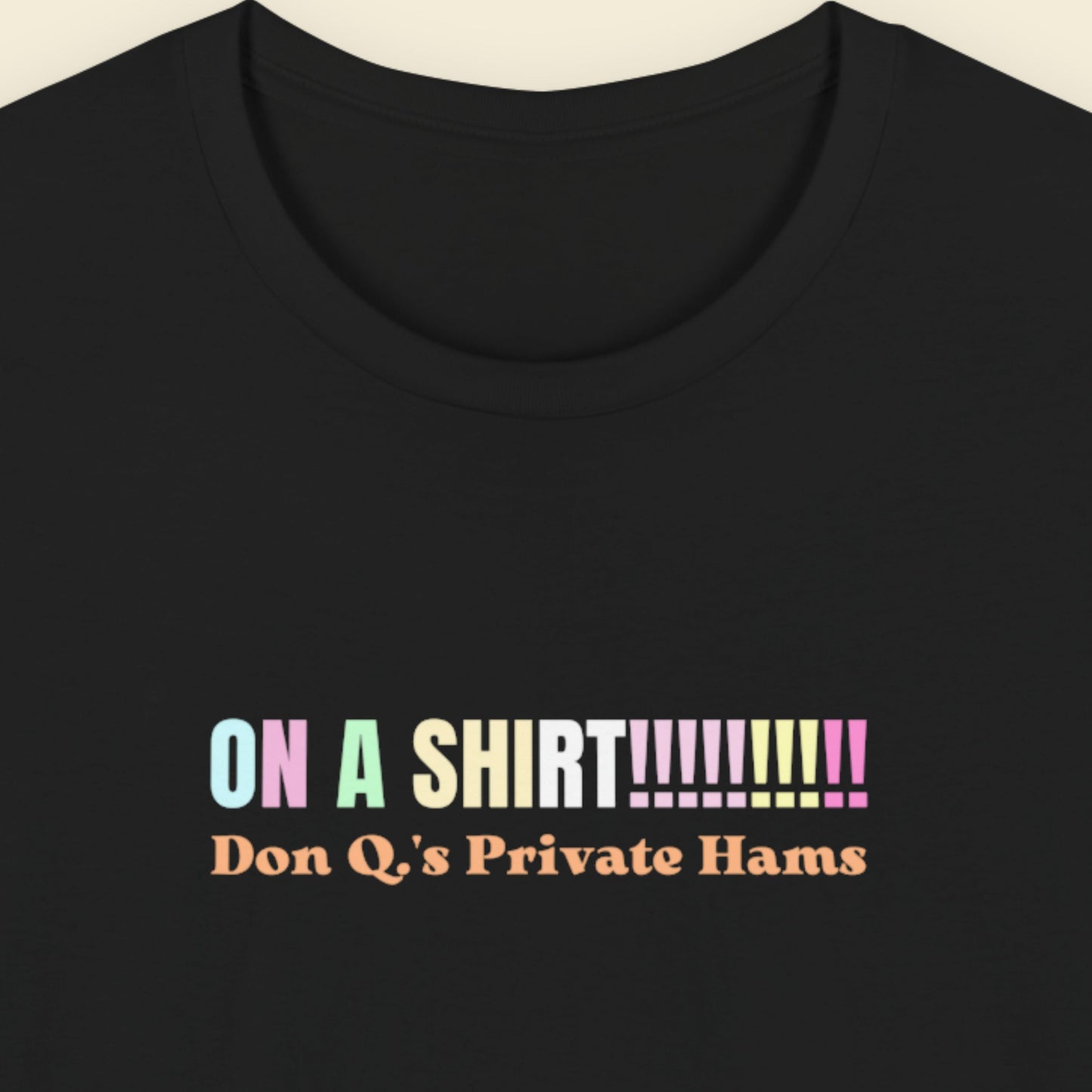 Black t-shirt with humorous colorful text on a beige background.