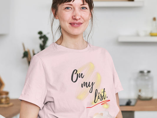 Woman wearing a pink t-shirt with text in a kitchen setting