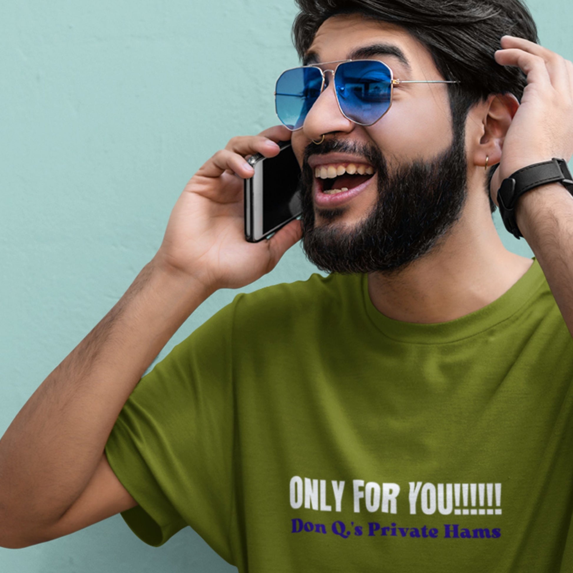 Man on phone wearing a green t-shirt with nonsensical text on a blue background.