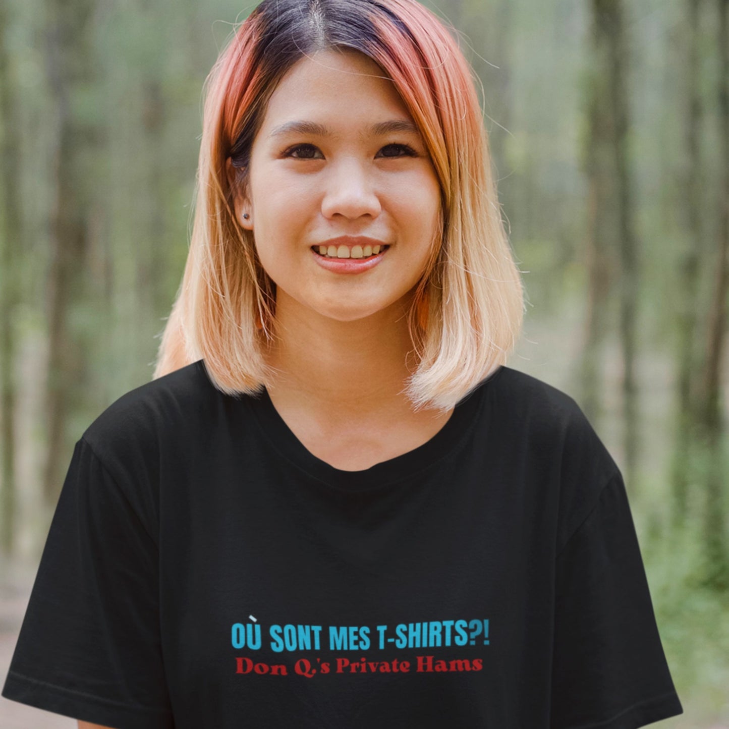 Woman in a forest wearing a black t-shirt with humorous colorful text.
