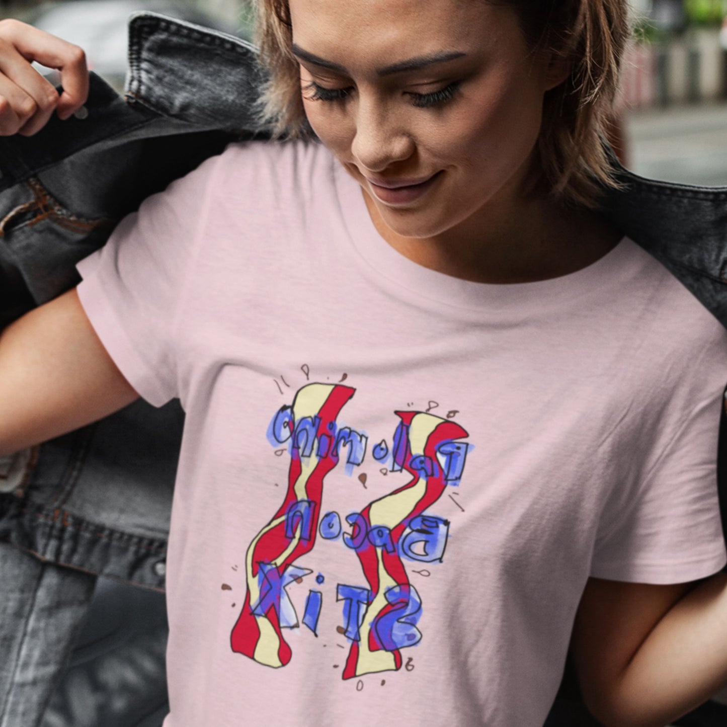 Woman wearing a pink t-shirt with a colorful abstract bacon drawing outside.
