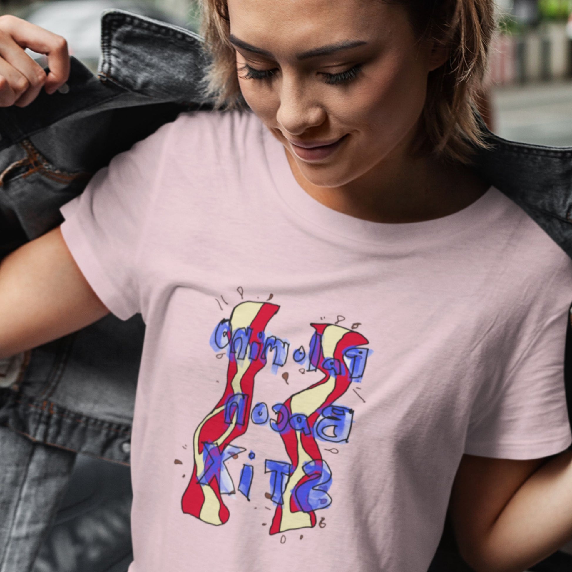 Woman wearing a pink t-shirt with a colorful abstract bacon drawing outside.