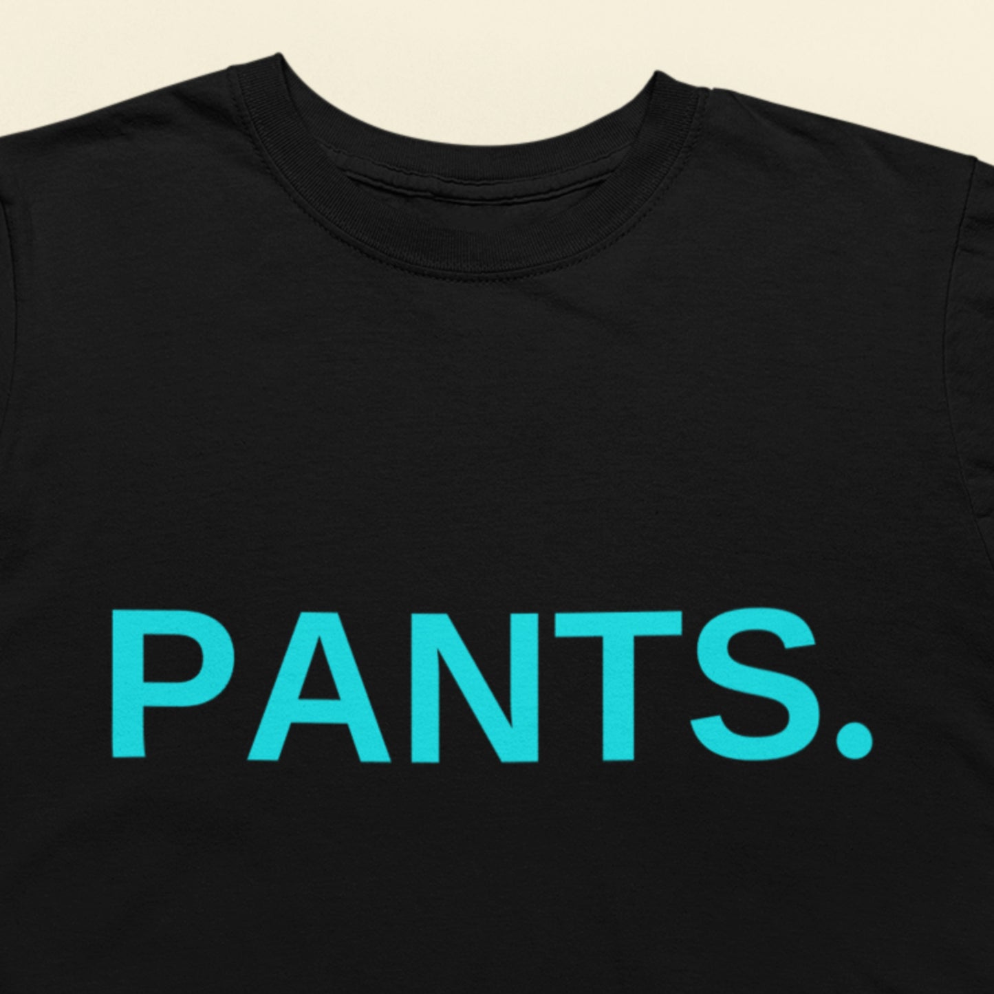 Black t-shirt with 'PANTS.' in blue text on a beige background