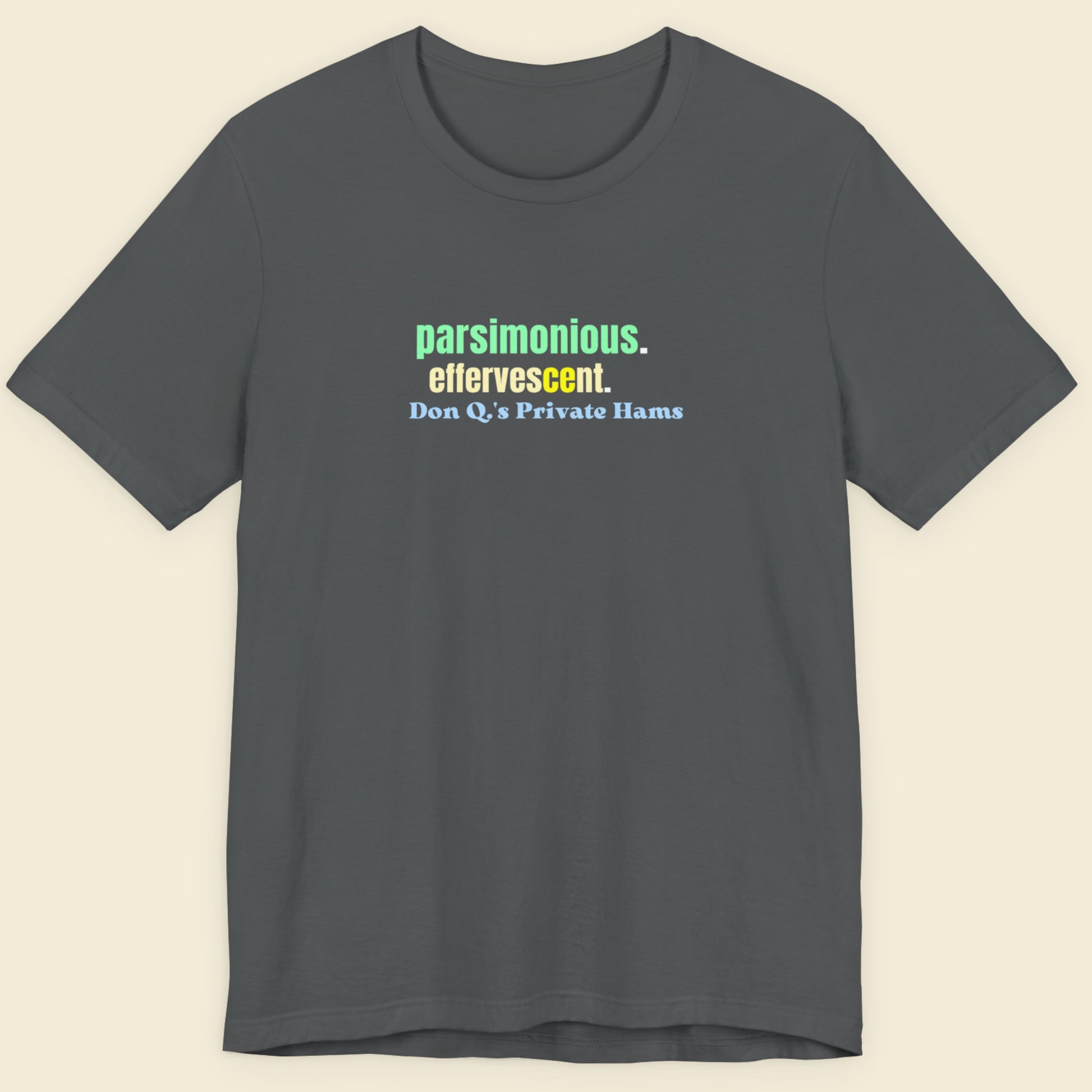 Dark grey t-shirt with humorous colorful text on a beige background.