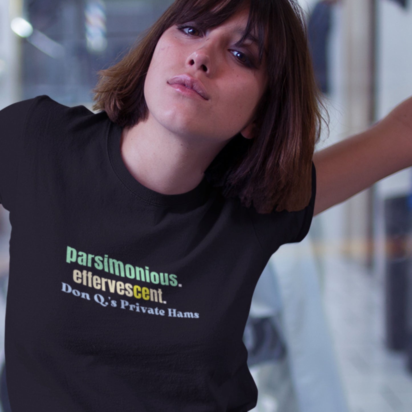 Woman wearing a black t-shirt with humorous colorful text in the city at night.