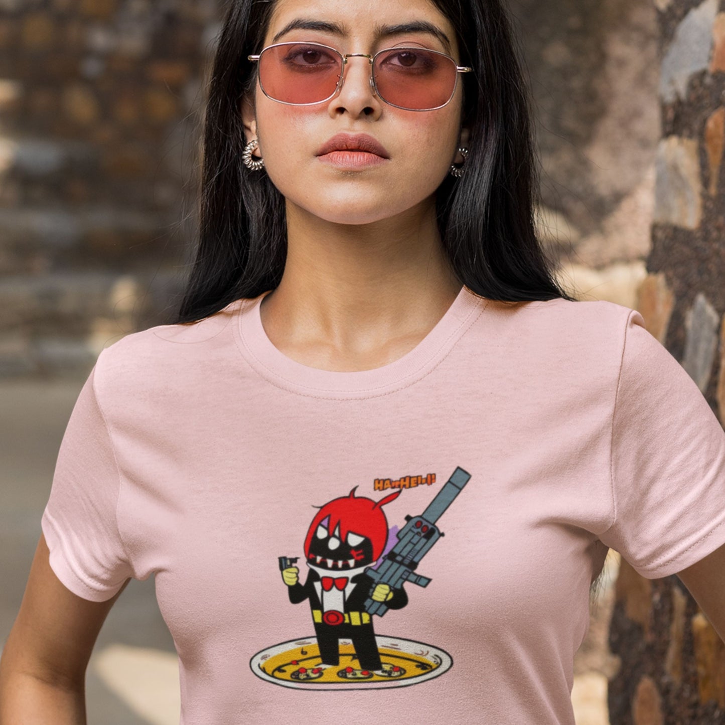 Upset woman wearing a pink t-shirt with a fun, colorful cartoon illustration outside.