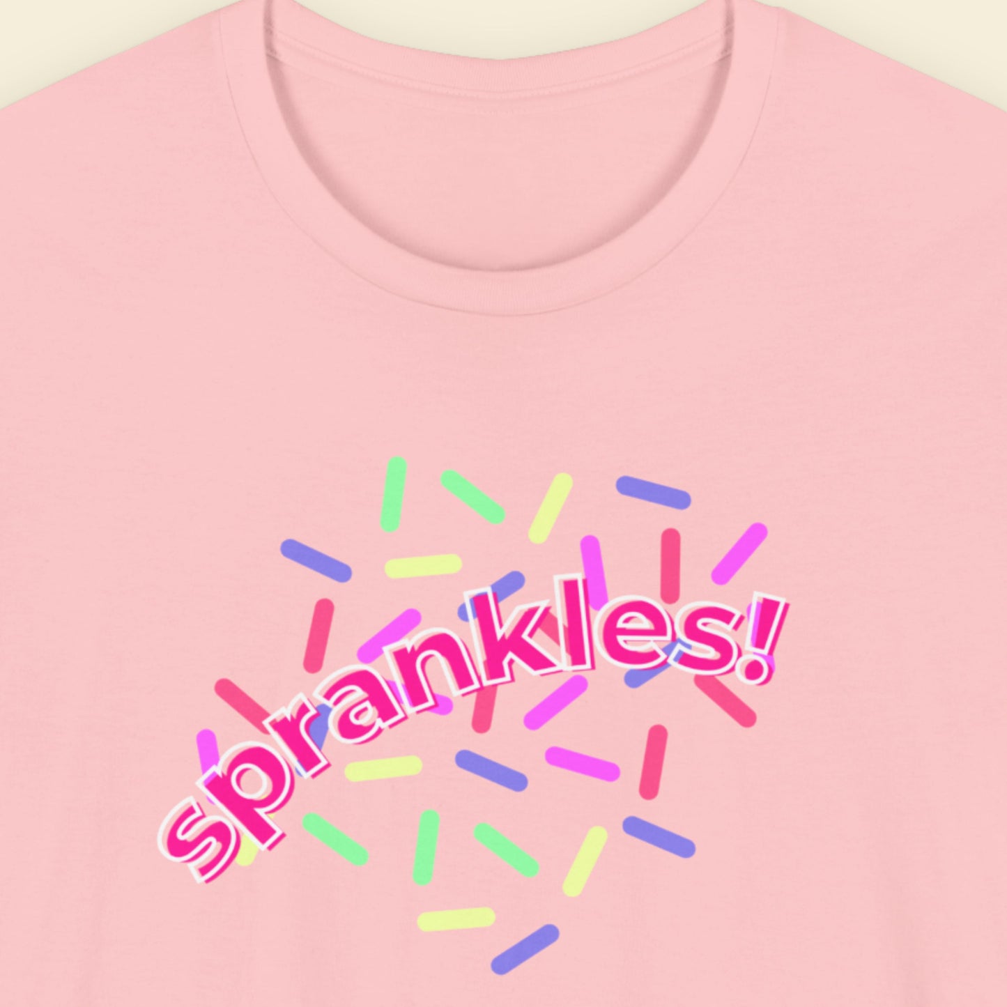 Pink t-shirt with humorous colorful text on a beige background.