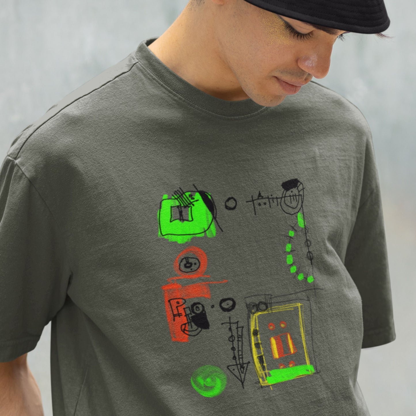 Man wearing an army green shirt with a colorful abstract drawing outside.