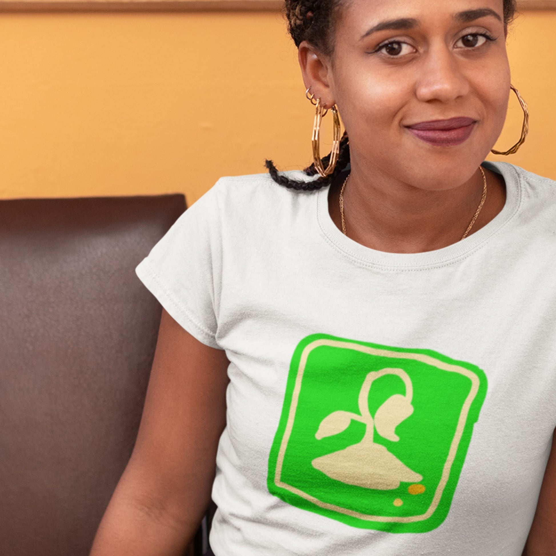 Person wearing a white t-shirt with a green graphic design on a yellow background.