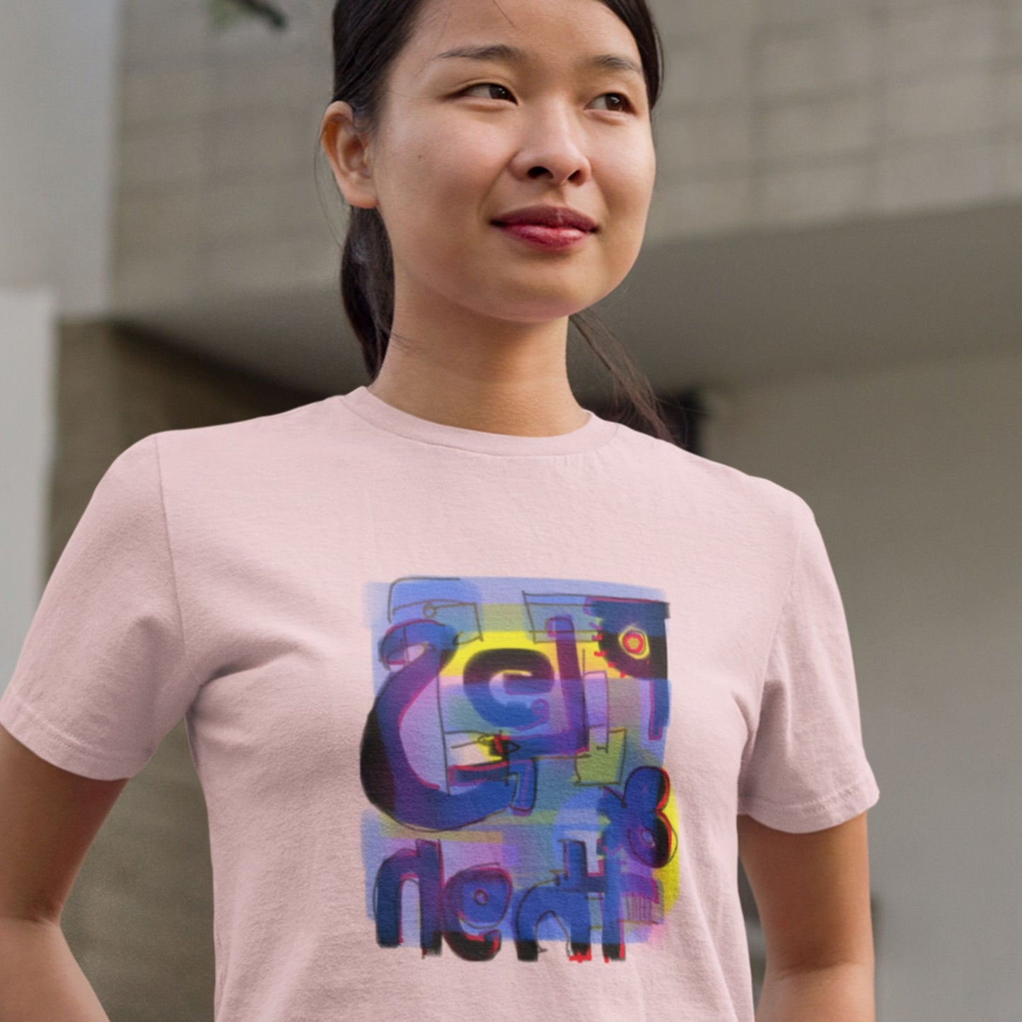 Woman about to laugh while wearing a pink t-shirt with a colorful abstract trash graff drawing in an office park.