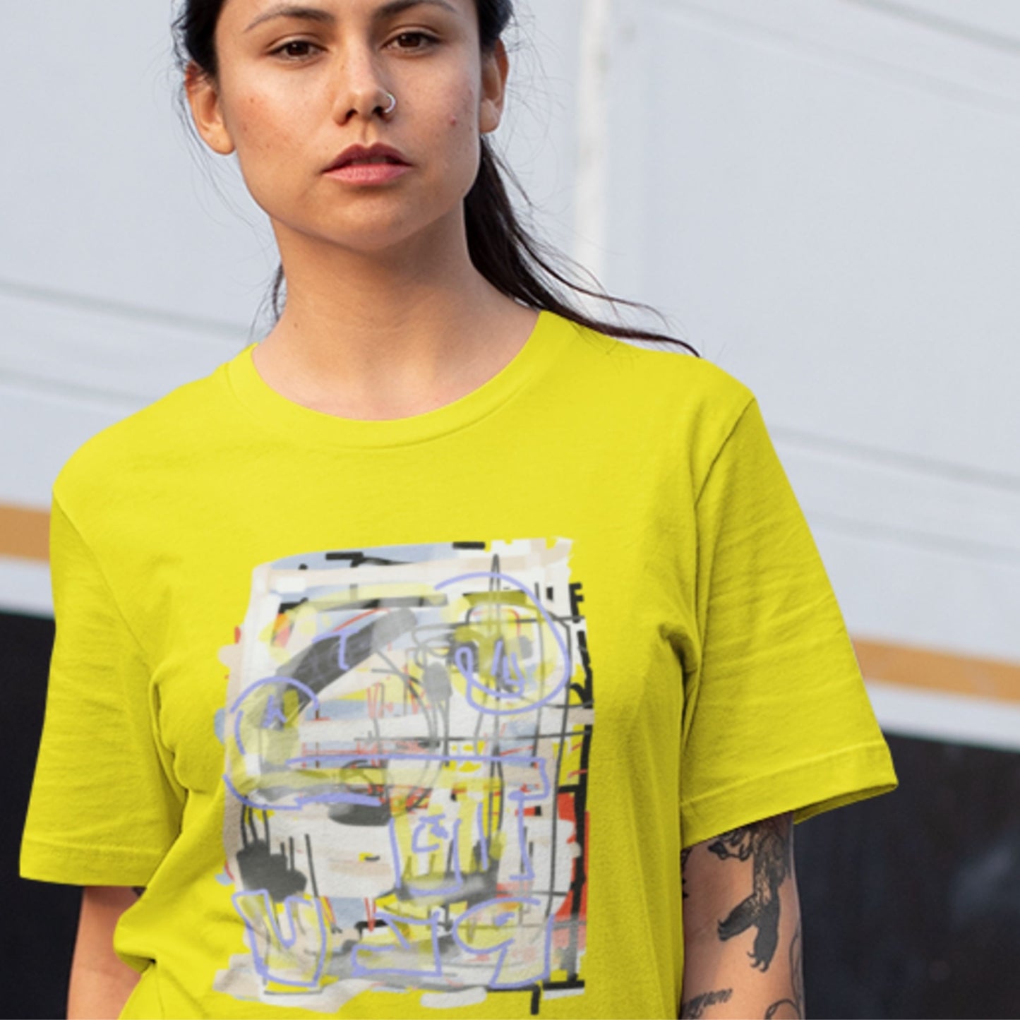 Woman wearing a yellow t-shirt with a colorful abstract drawing outside.