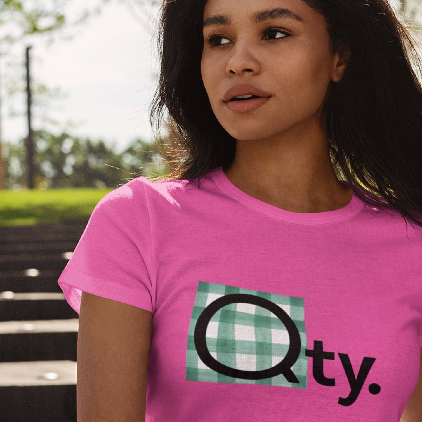 Woman wearing a pink t-shirt with a graphic design outdoors.