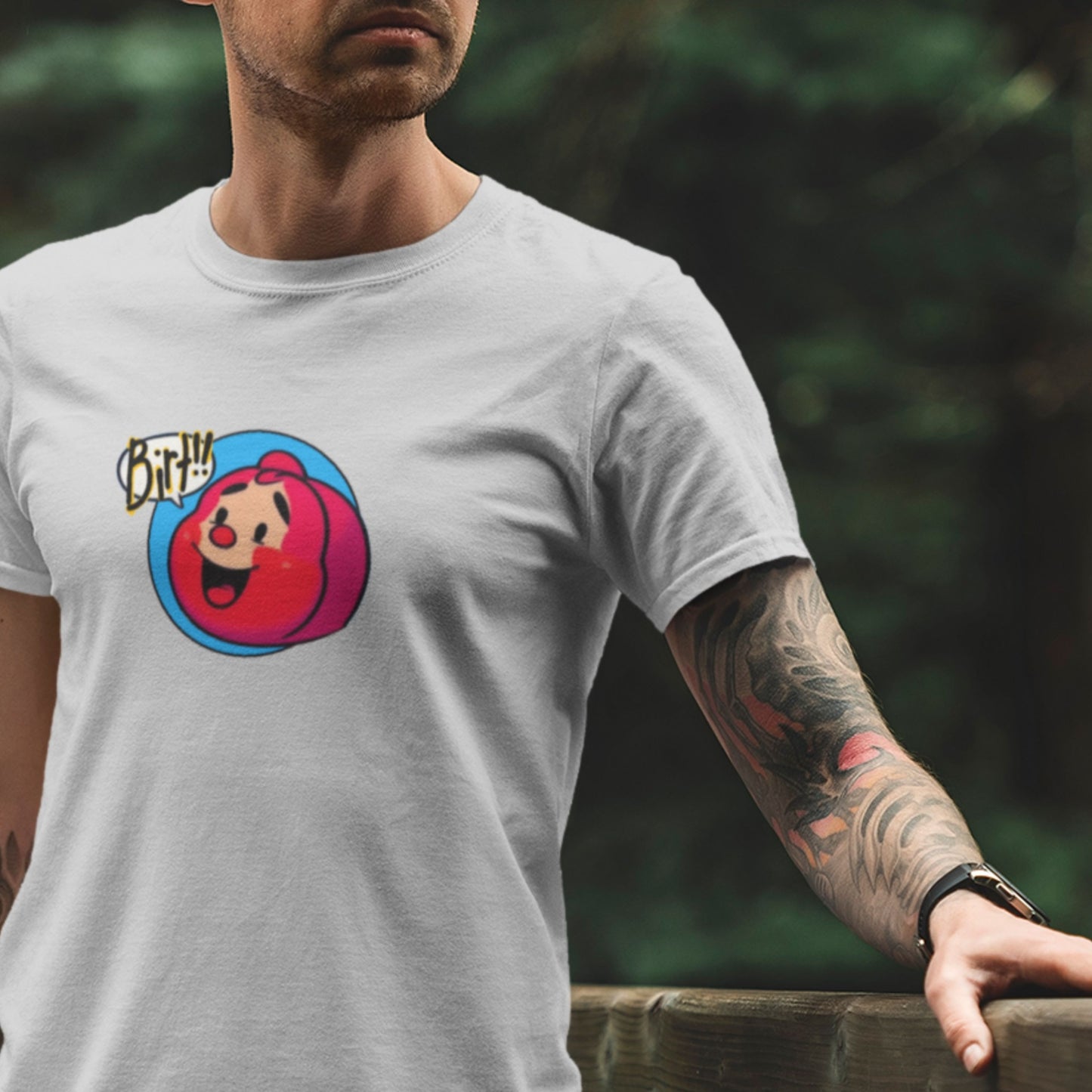 Person wearing a grey t-shirt with a colorful graphic design, standing outdoors.