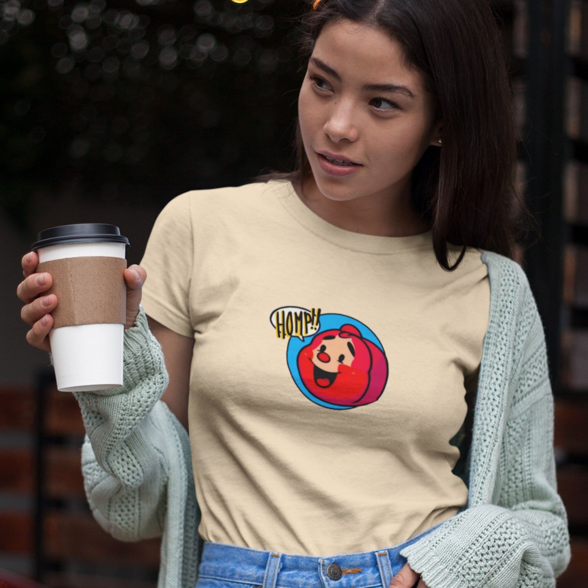 Woman wearing a beige t-shirt with a colorful graphic design, holding a coffee cup.