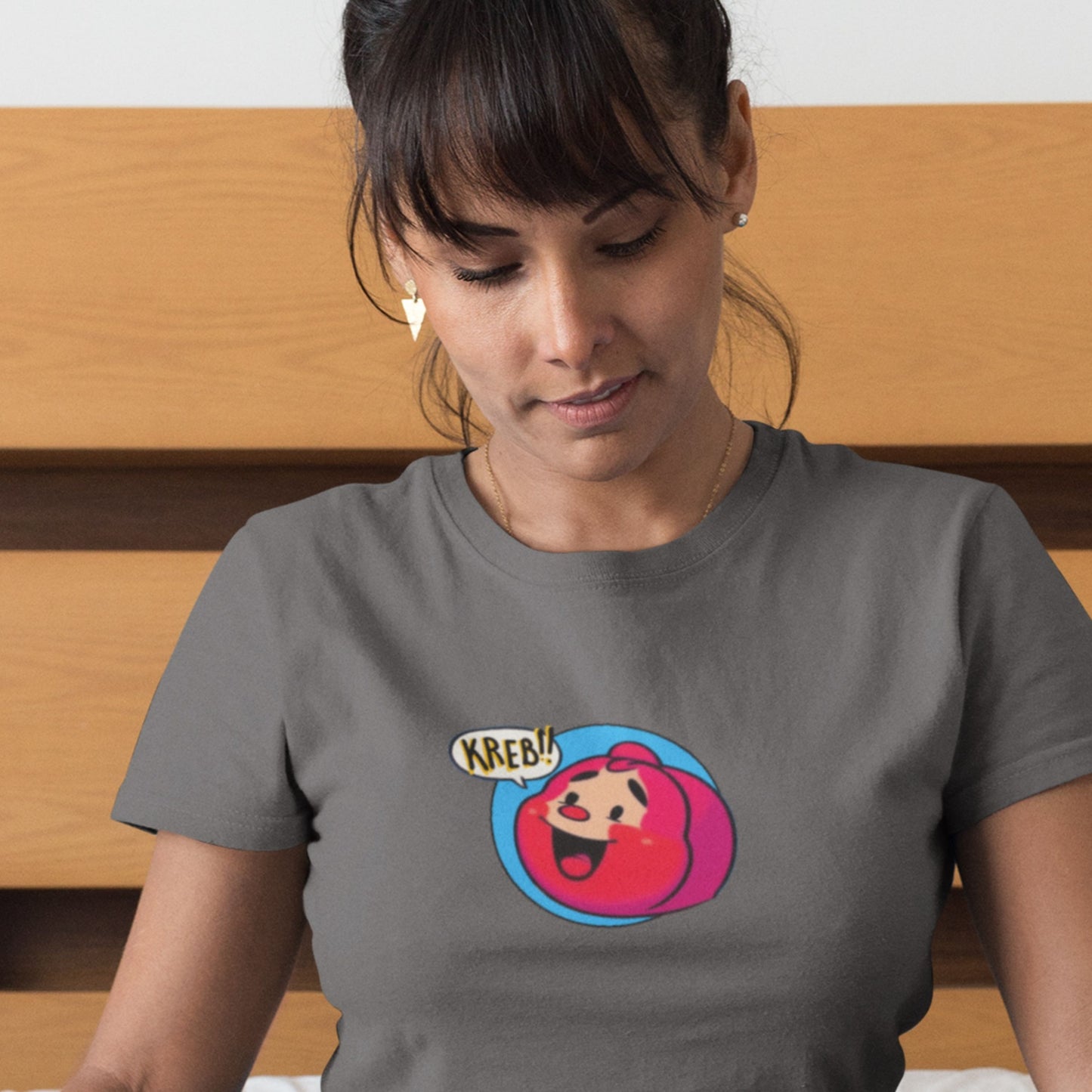 Woman wearing a gray t-shirt with a colorful graphic design on a wooden surface.