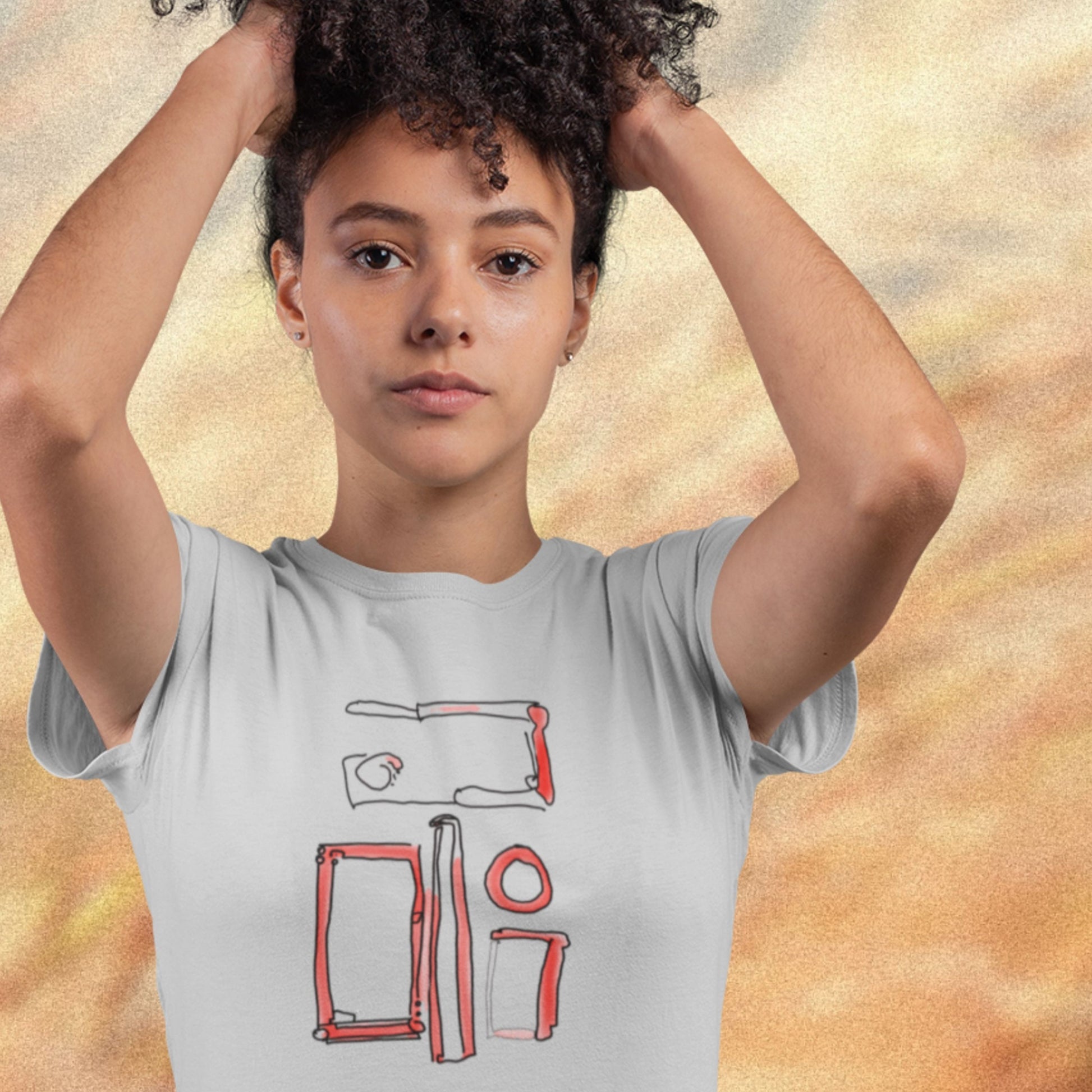 Model wearing a light grey t-shirt with a colorful abstract drawing on a blurry background.