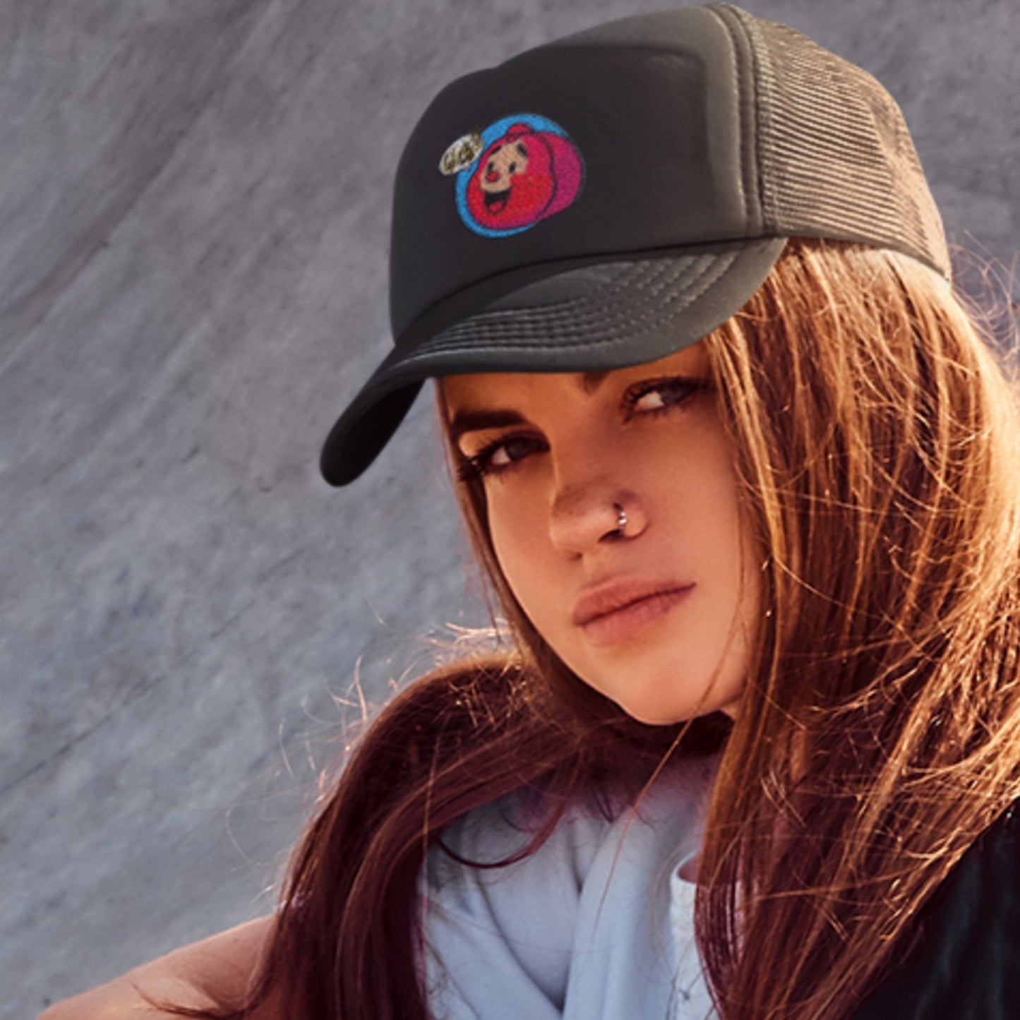 Woman wearing a black cap with a colorful logo against a gray background.