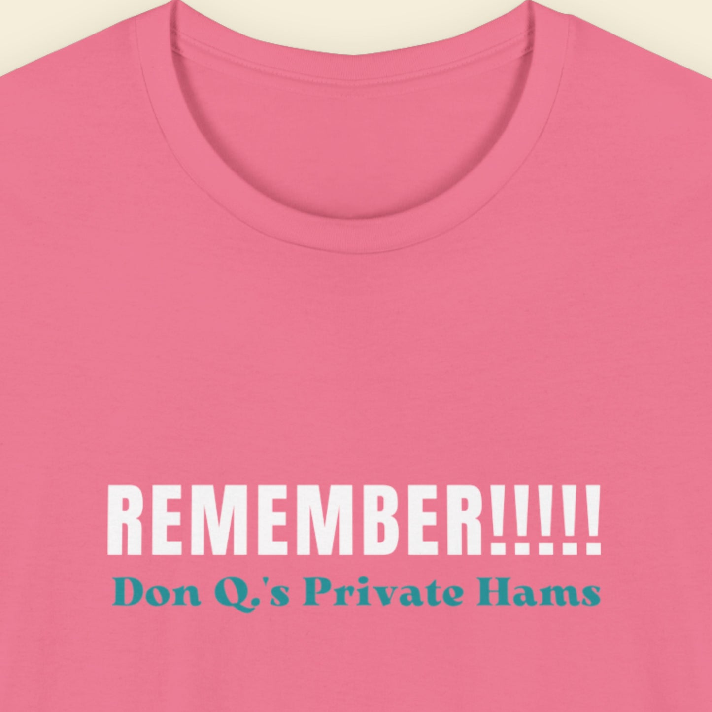 Pink t-shirt with white and blue text on a beige background.