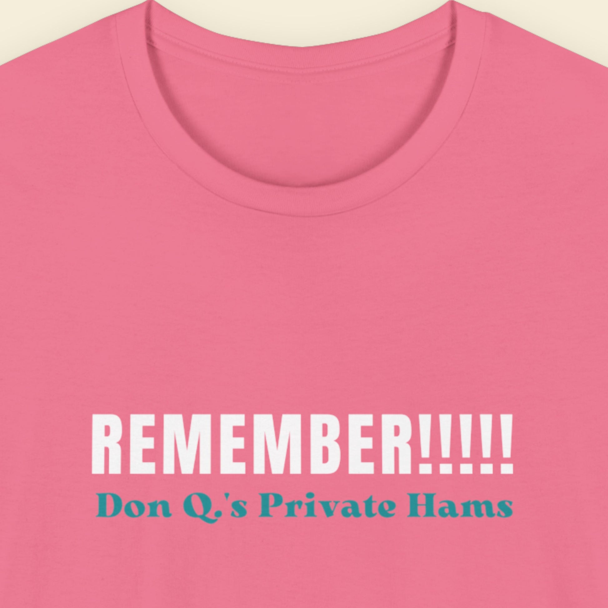 Pink t-shirt with white and blue text on a beige background.