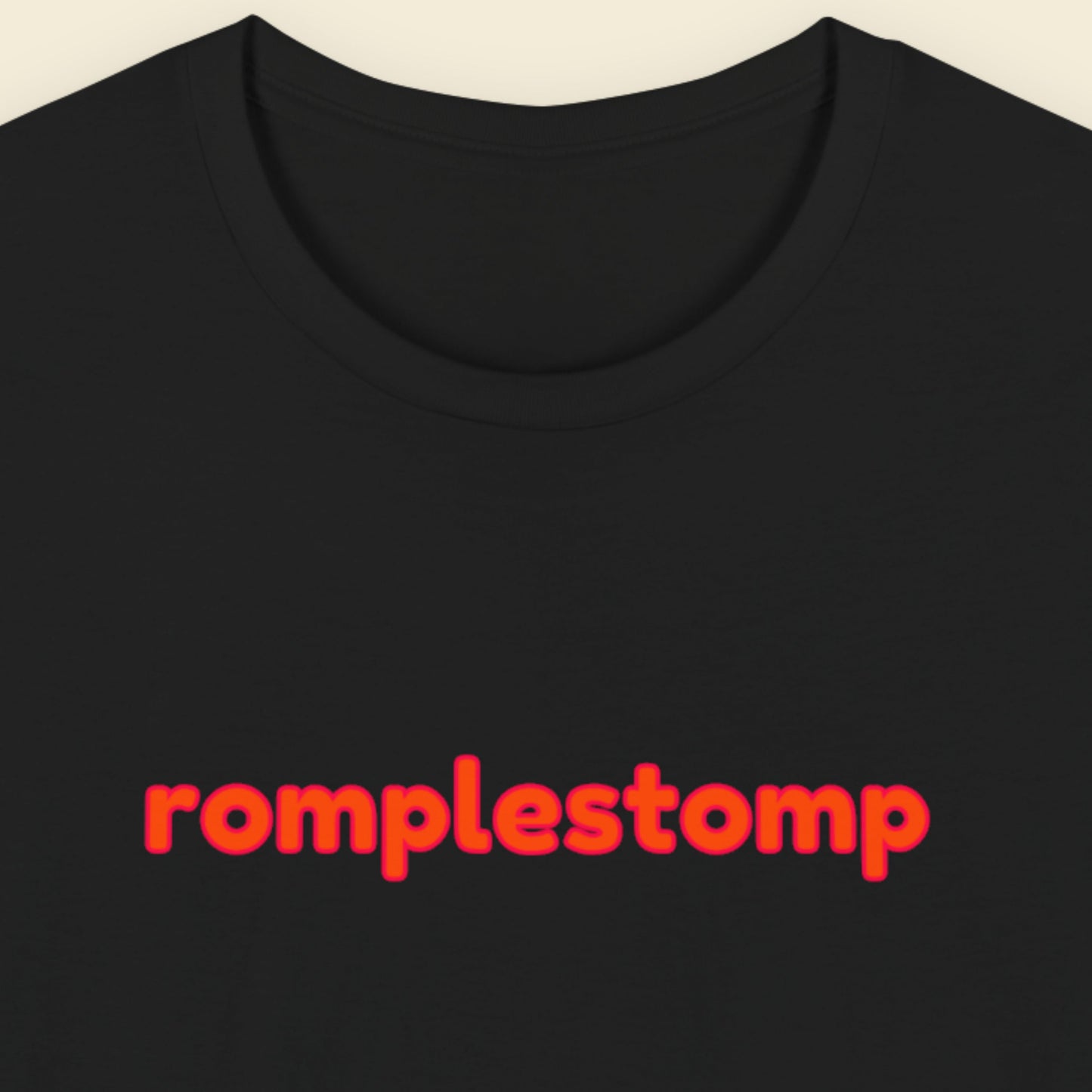 Black t-shirt with multicolored 'romplestomp' text on a beige background.