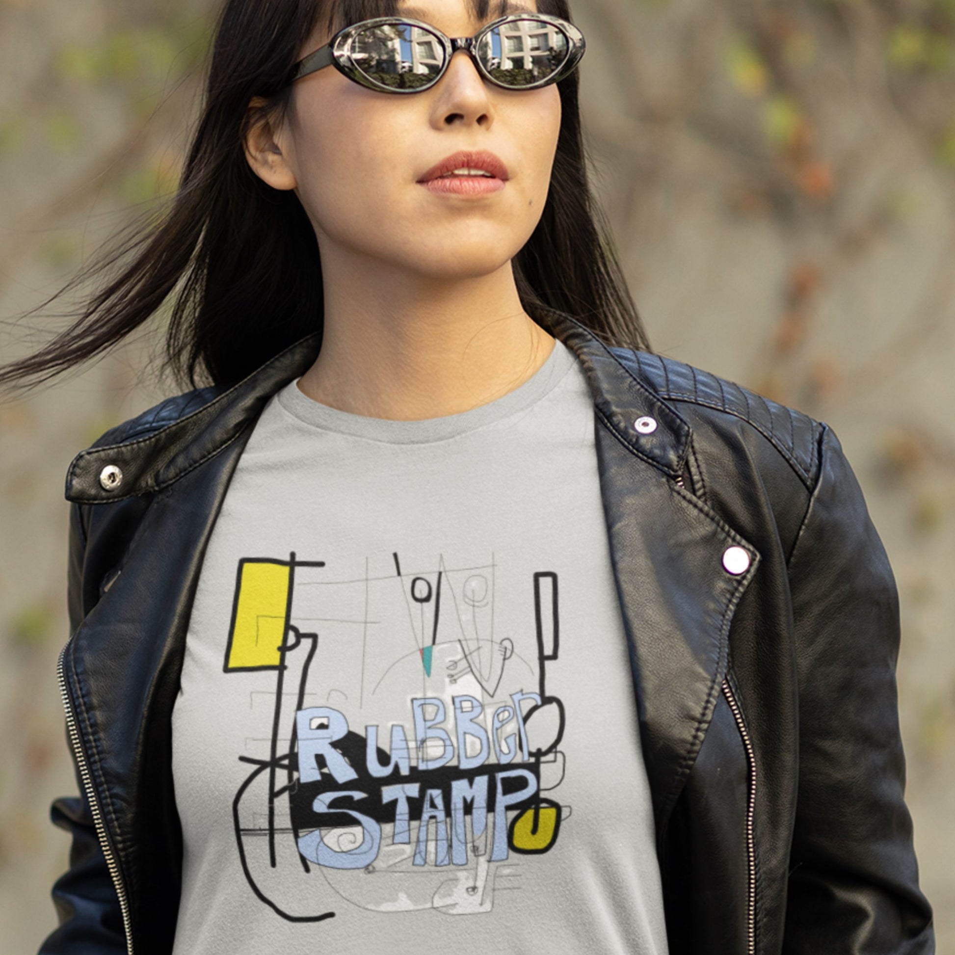 Cool girl wearing a gray t-shirt with graphic design and black leather jacket outdoors.
