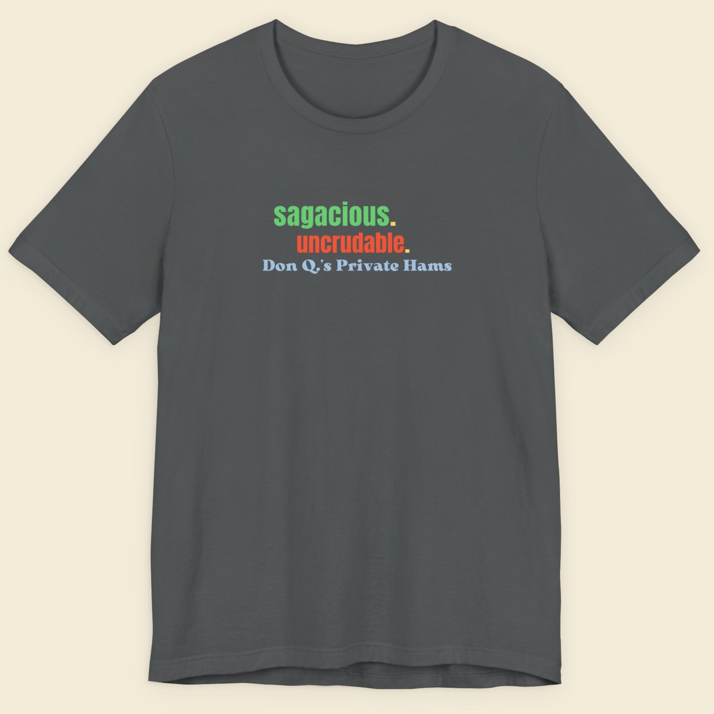 Dark grey t-shirt with humorous colorful text on a beige background.