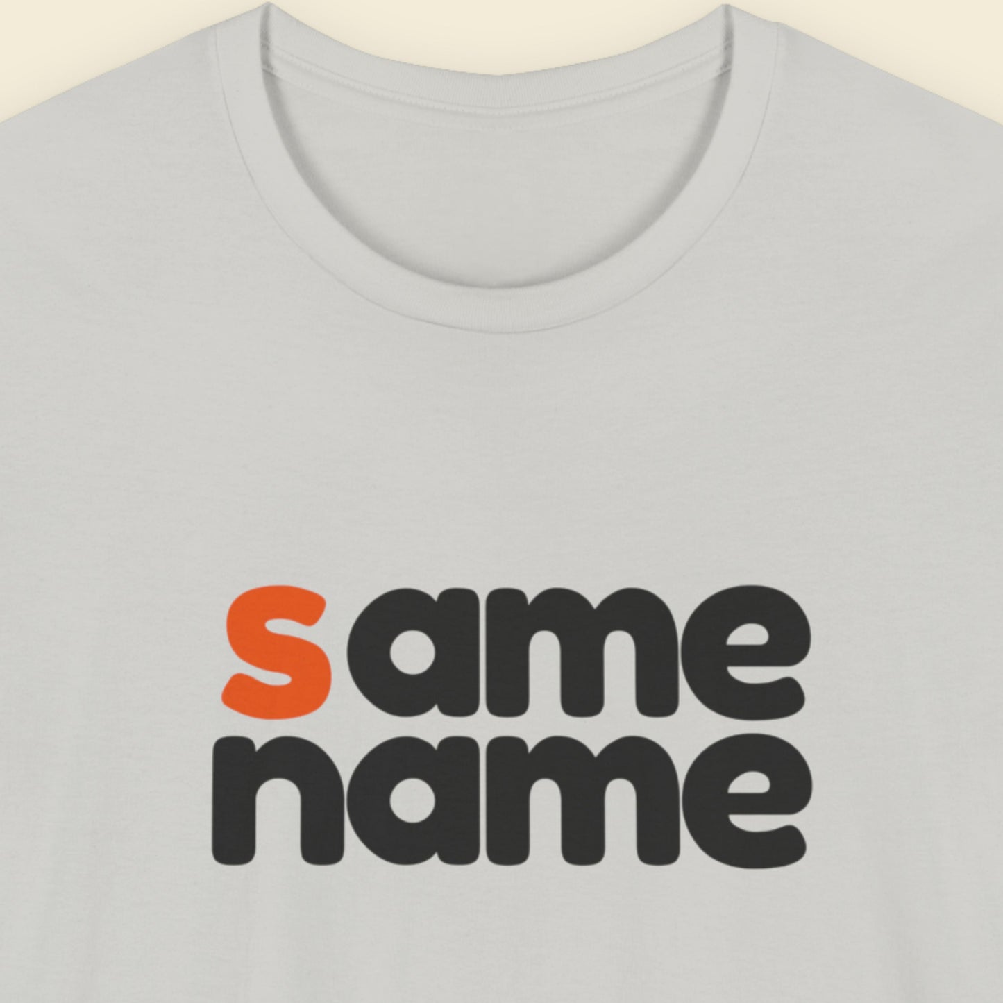 Light grey t-shirt with humorous colorful text on a beige background.