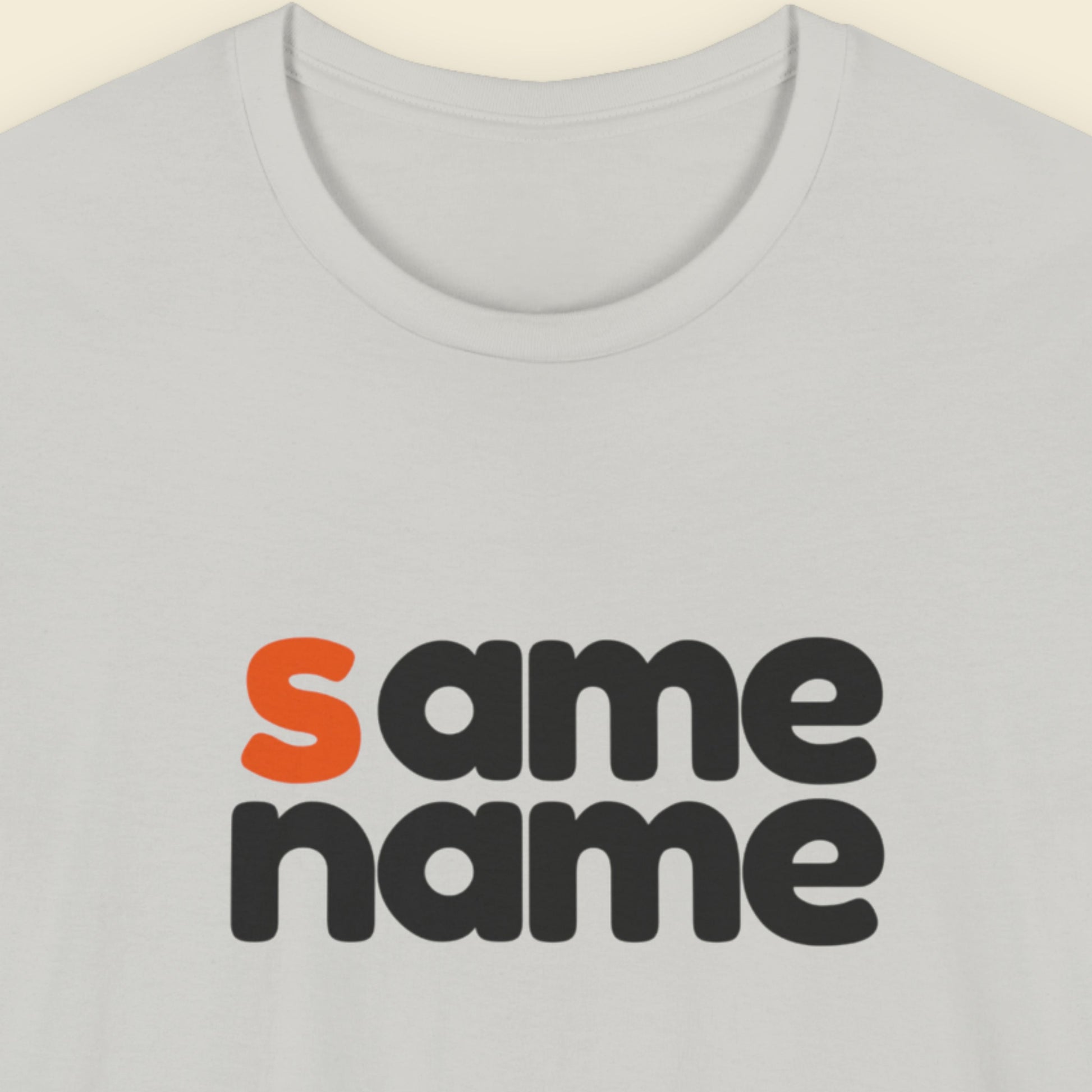 Light grey t-shirt with humorous colorful text on a beige background.