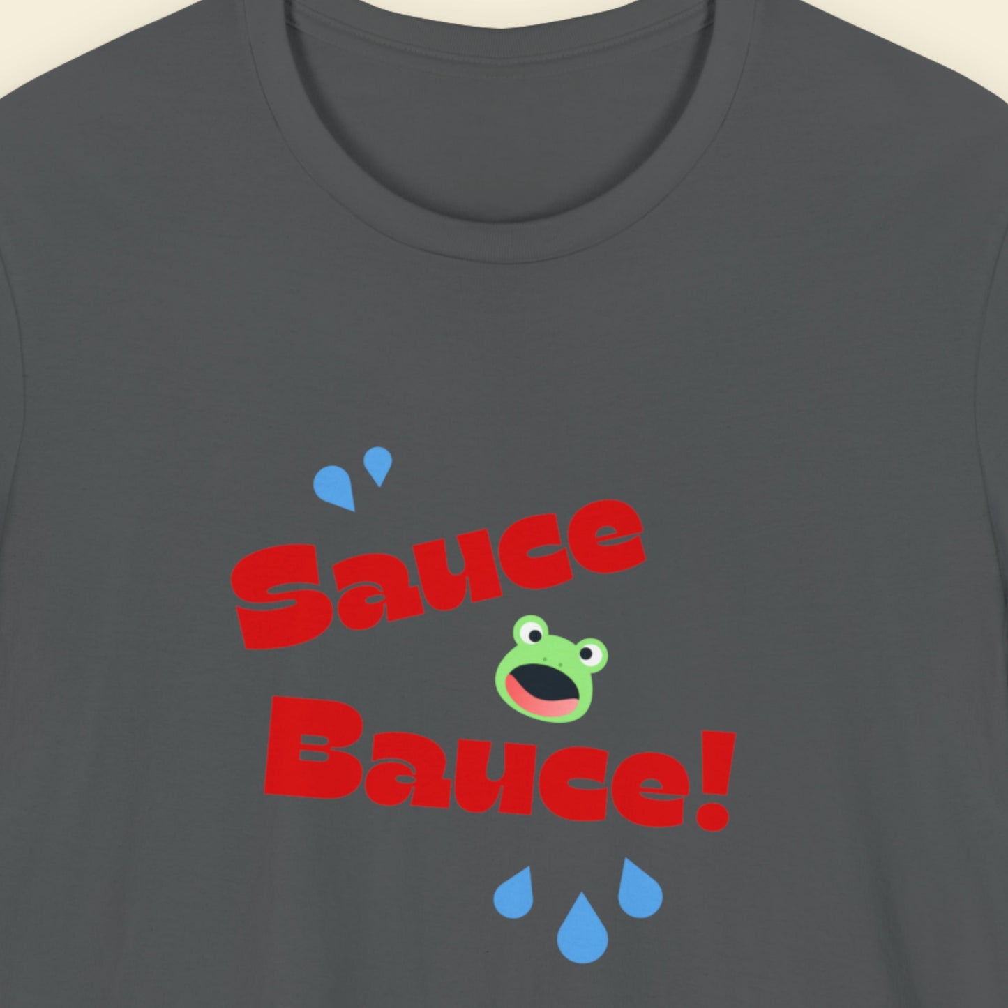 Gray t-shirt with 'Sauce Bauce!' text and cartoon frog design on a beige background.