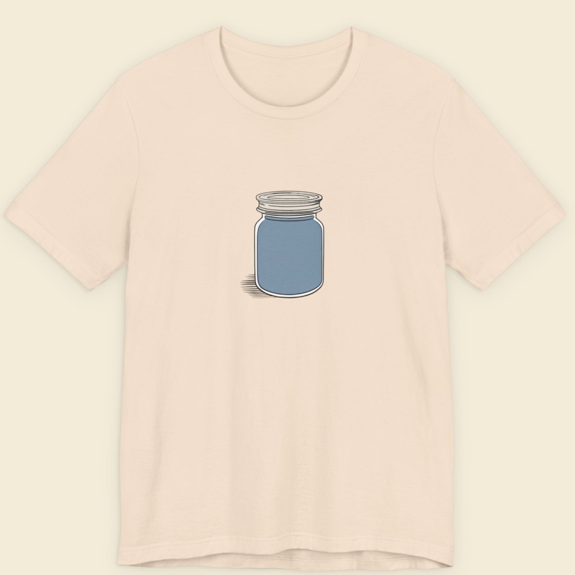 Beige shirt with a drawing of a screw top jar full of something blue.