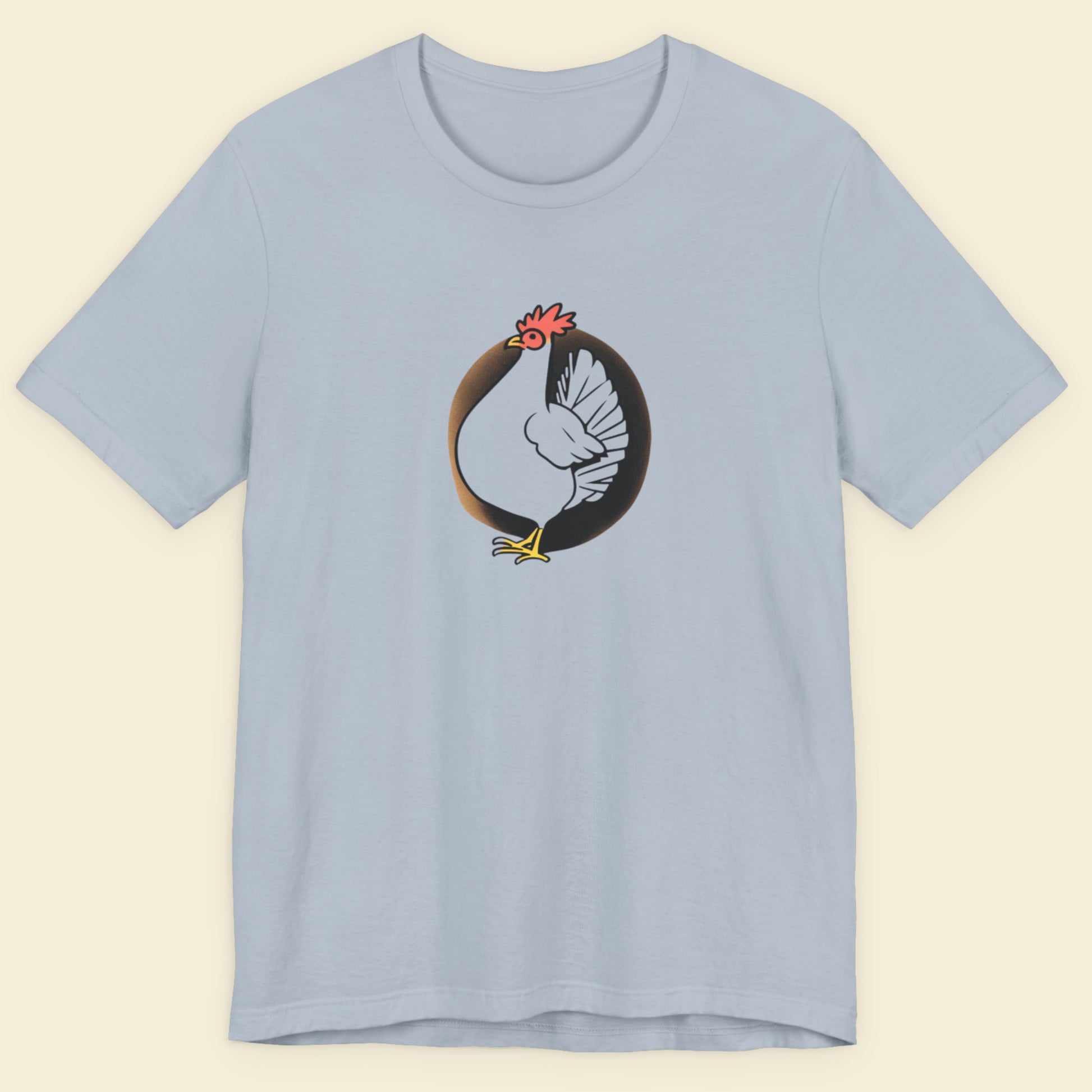 Light blue t-shirt with a drawing of a chicken on a beige background.