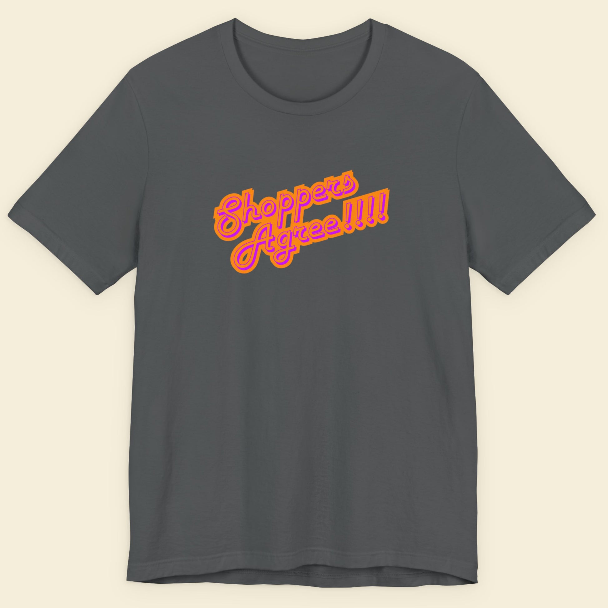 Grey t-shirt with humorous colorful text on a beige background.