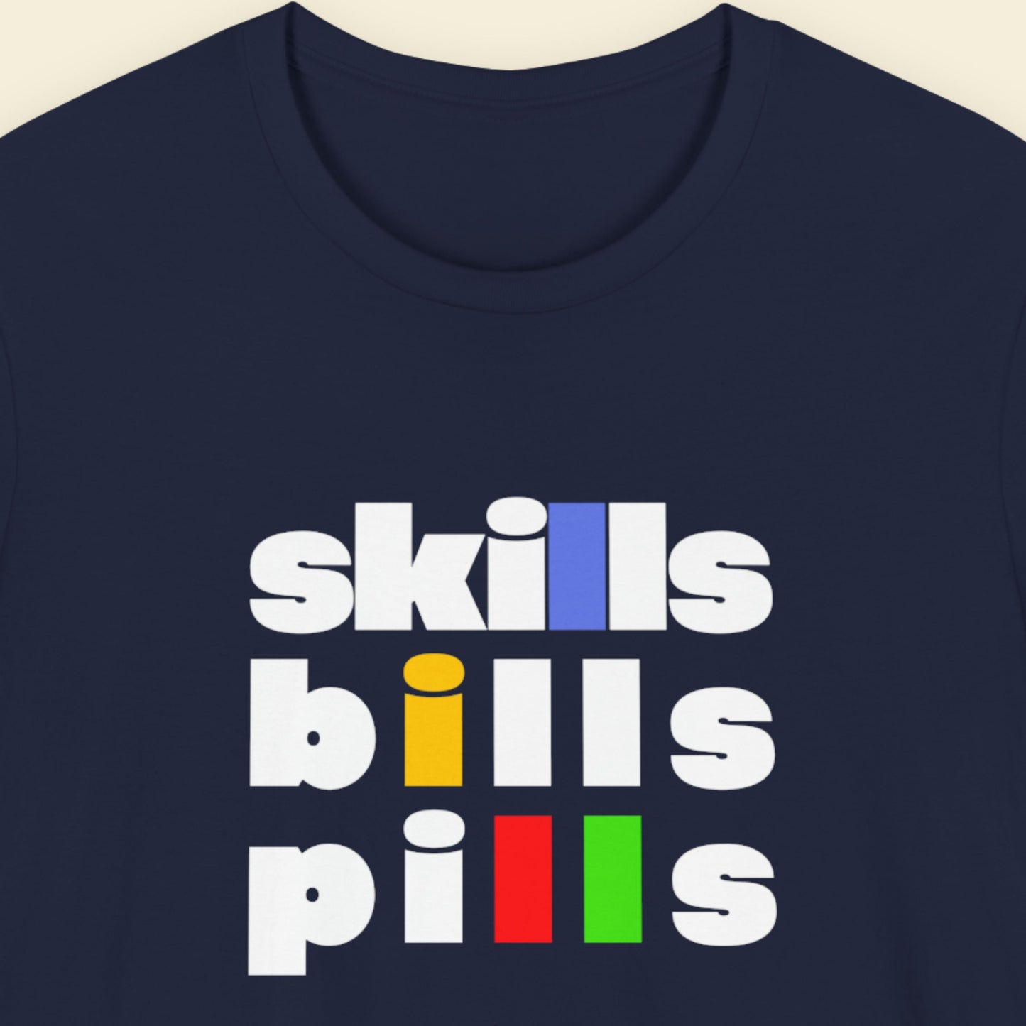 Navy blue t-shirt with 'skills bills pills' text in colorful letters on a beige background.
