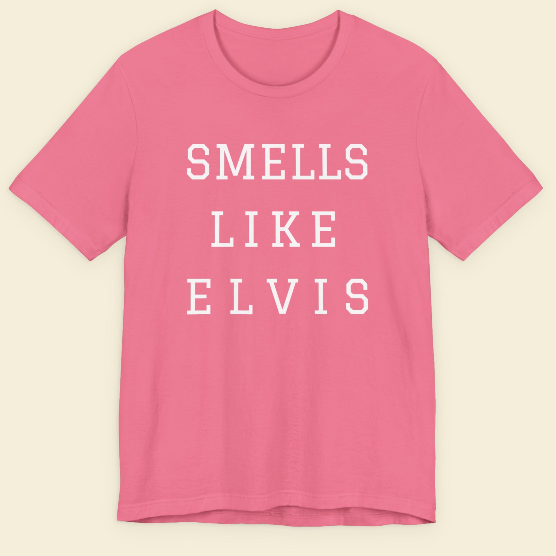 Pink t-shirt with 'SMELLS LIKE ELVIS' text on a beige background.